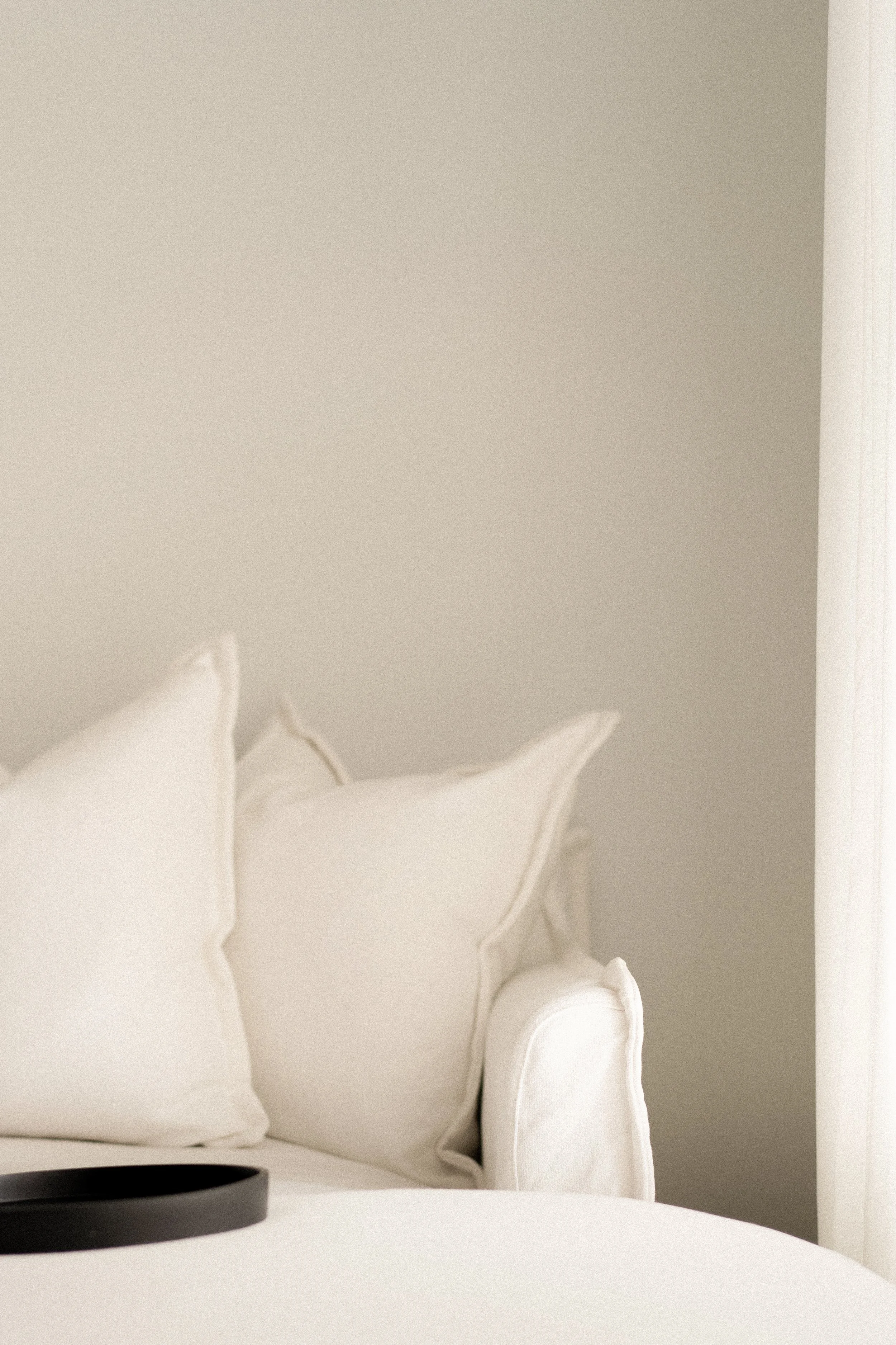 Minimalist white sofa with pillows and a black tray.