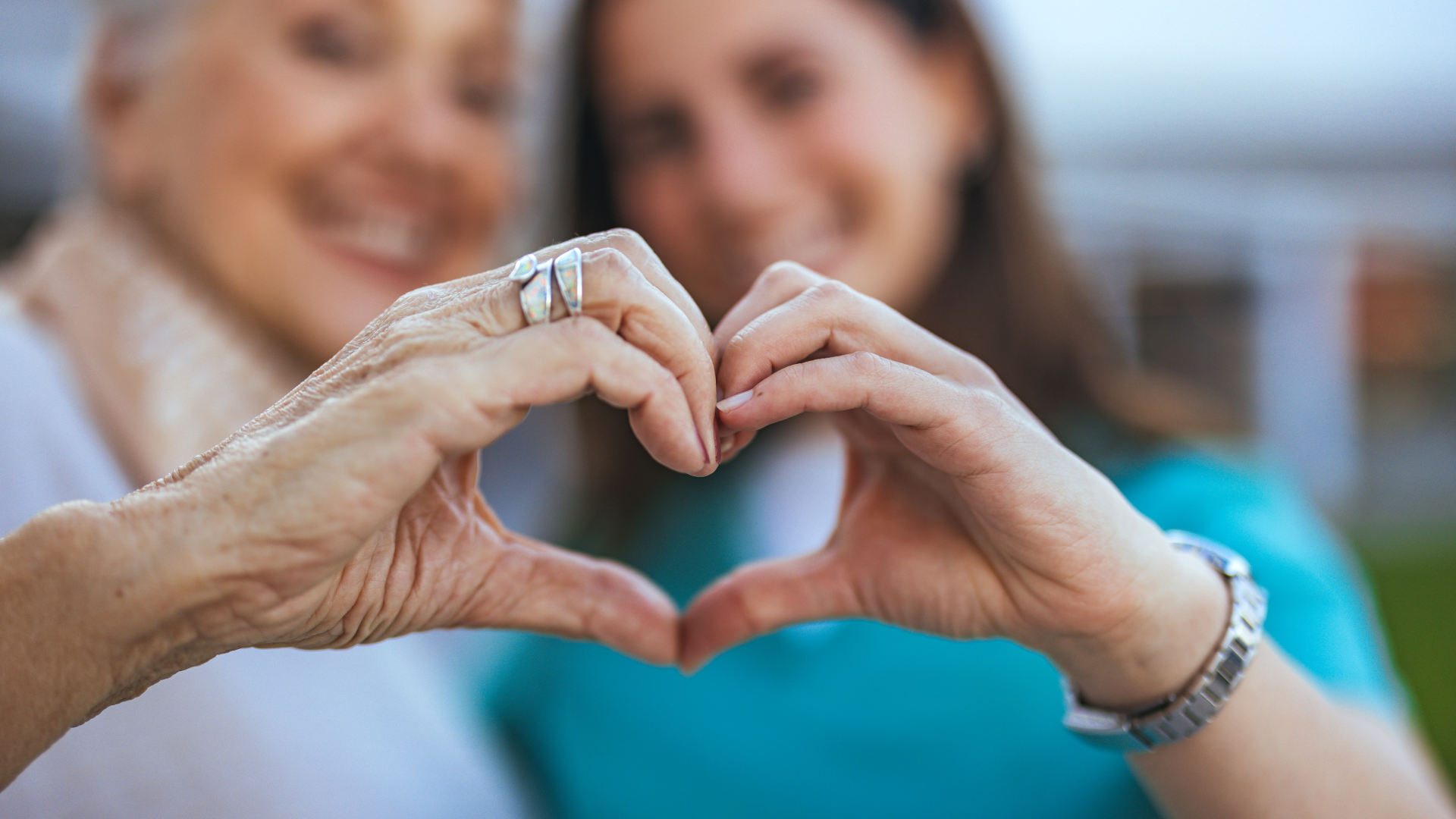 Scenic view of a turquoise lake surrounded by grassy hills and distant mountains under a cloudy sky.