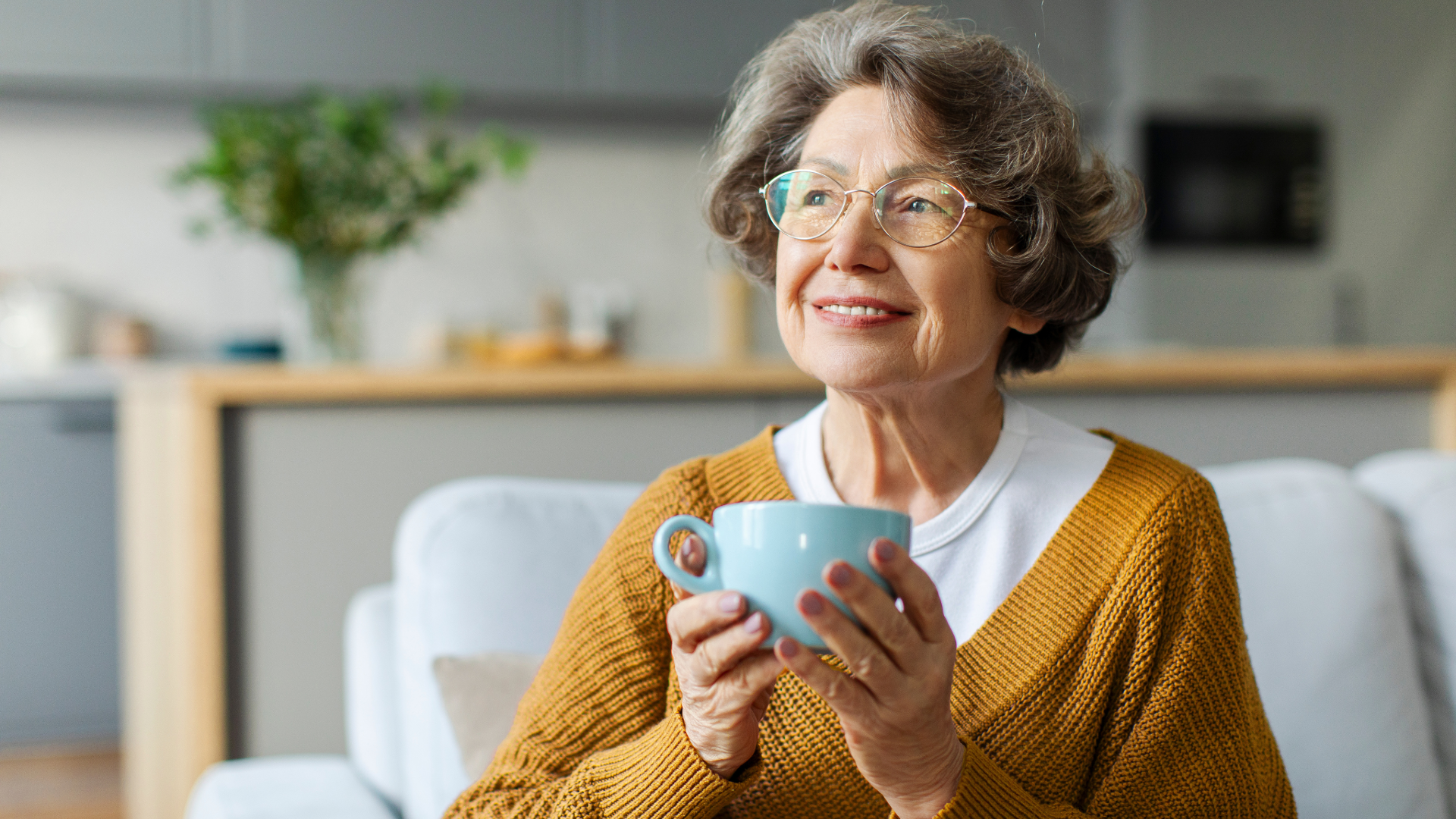 Snowy mountain range with a modern building on a grassy hill in the foreground.