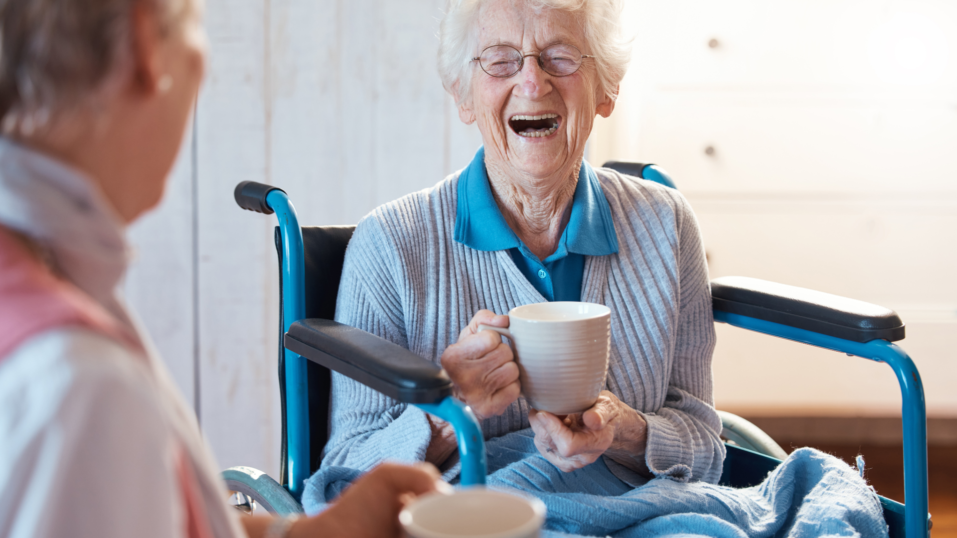 Modern wooden house in mountain landscape with large window and grassy foreground.