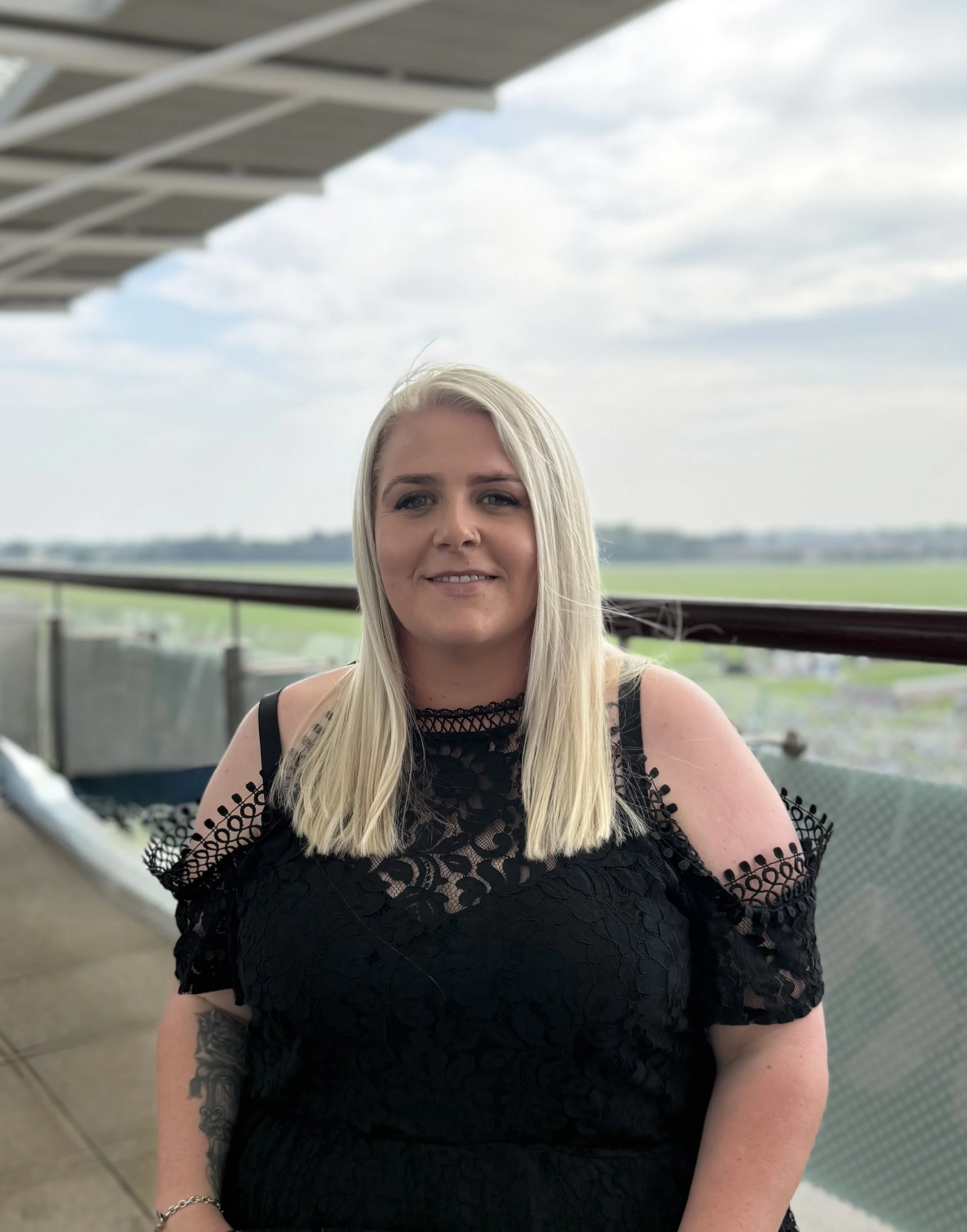Female with short blonde hair, wearing a floral black and white top