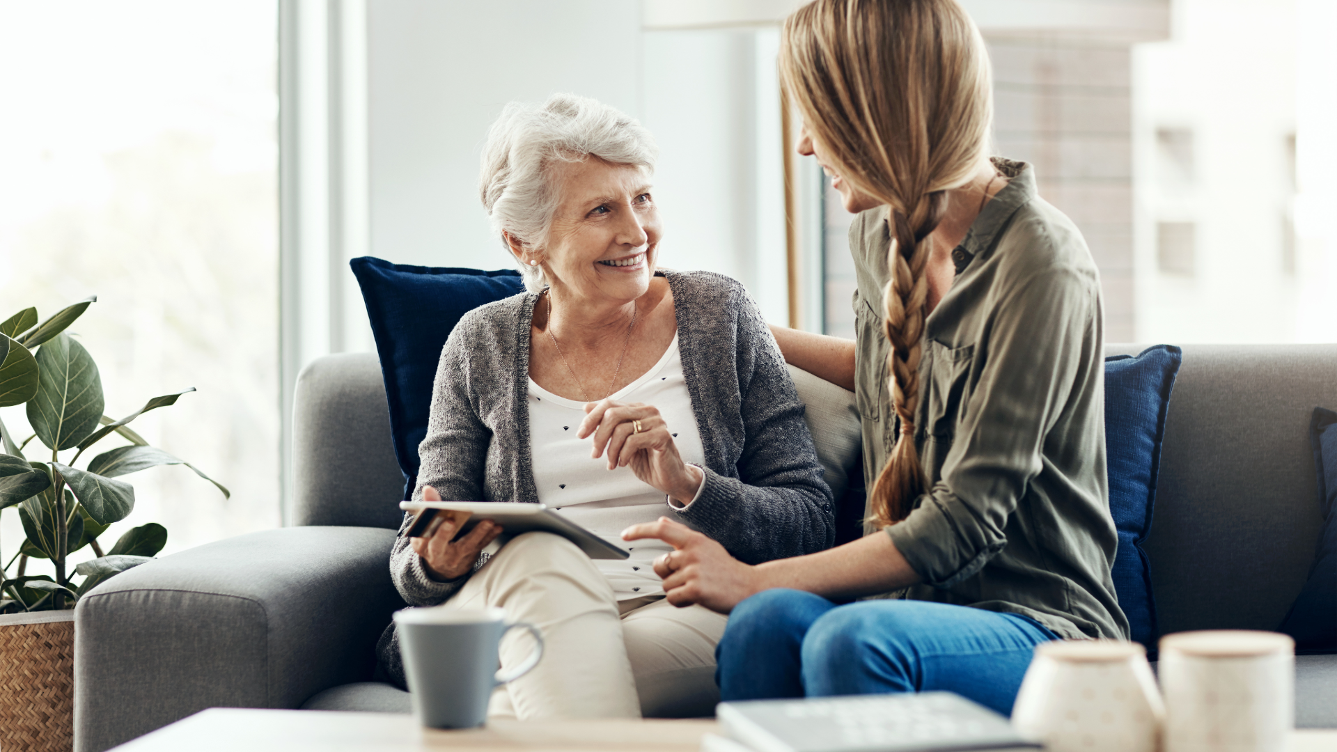 Landscape view of a modern wooden house with mountains and a lake in the background during sunset.