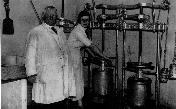 Two people operating vintage dairy equipment in a processing facility on New Manor Farm.