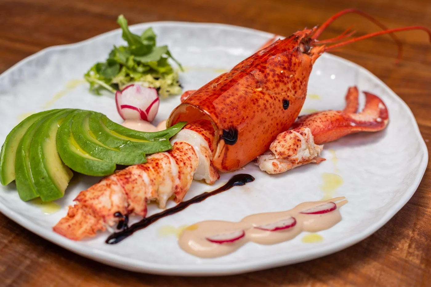 Camarón cocido y preparado en un plato con aguacate, ensalada y salsas.