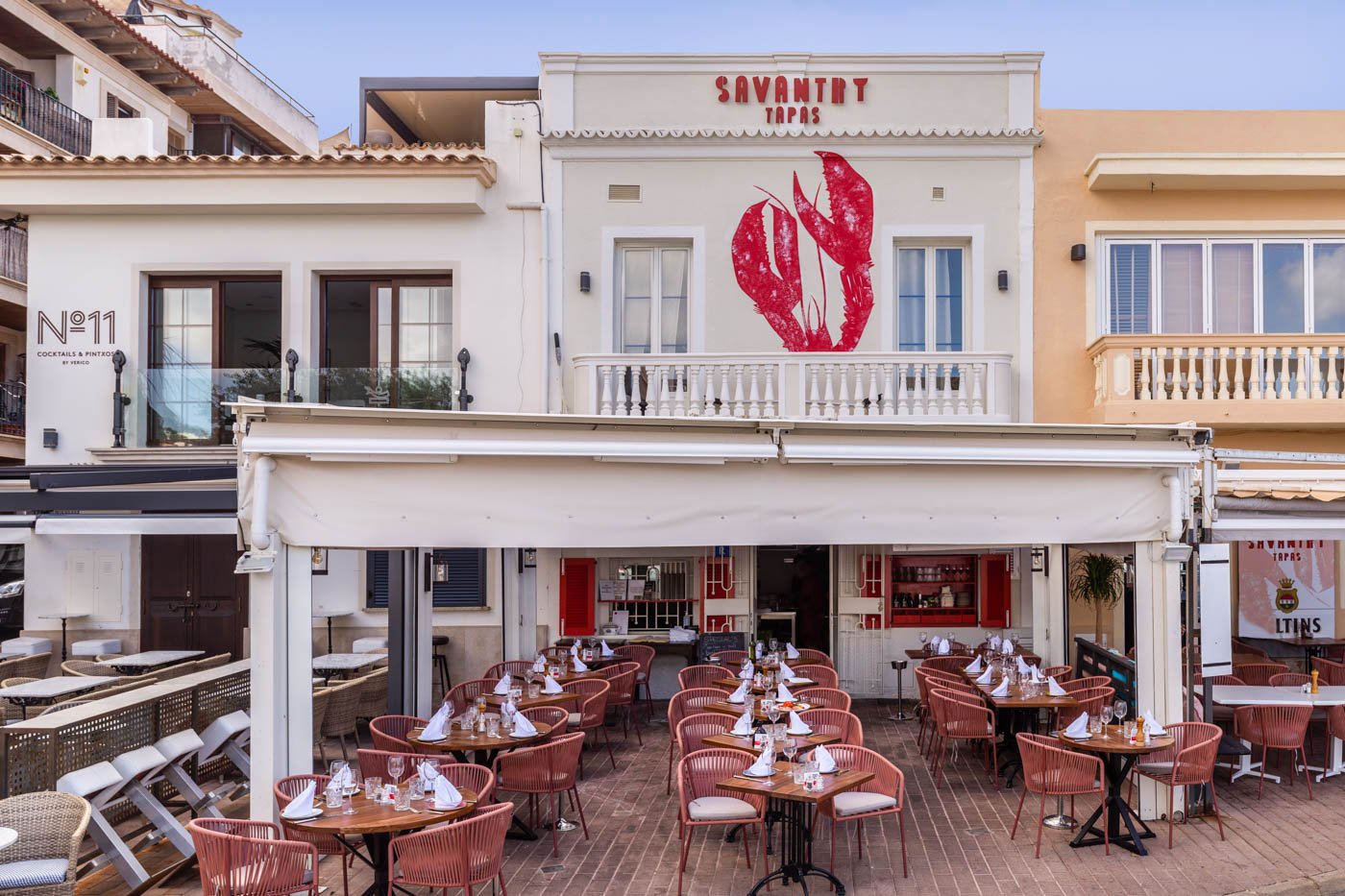 Fachada de un restaurante llamado Savantry Tapas con terraza al aire libre y decoración con un gran dibujo de langosta en la pared