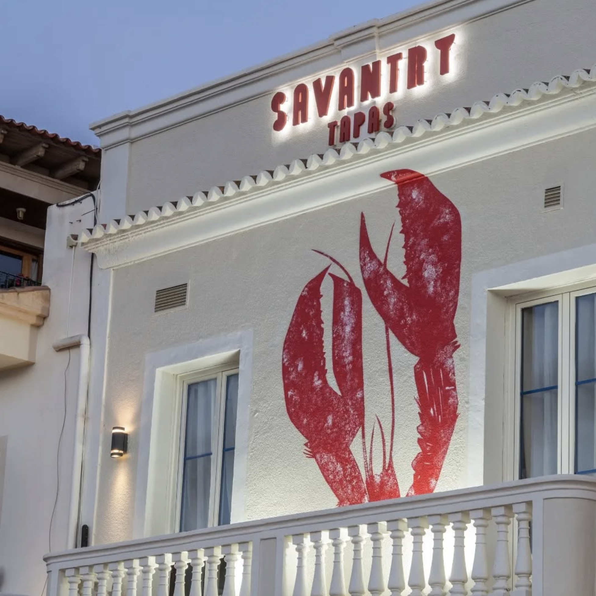 Fachada de un restaurante llamado 'Savant Tapas' con un mural de langosta en la pared exterior