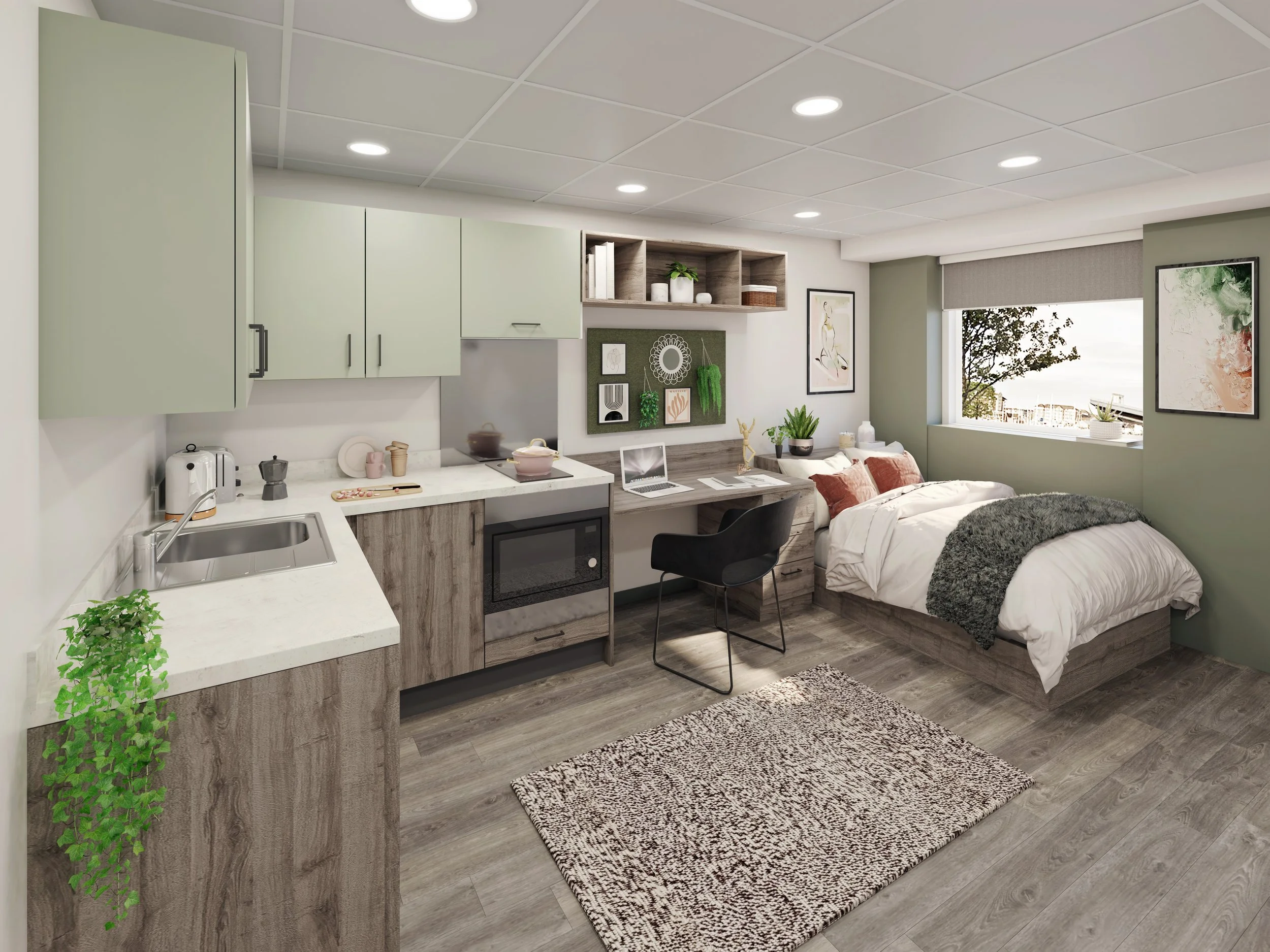 Modern studio apartment interior with a kitchenette featuring green cabinets and wooden accents, a sink, microwave, and countertop decor. Adjacent to the kitchenette is a cozy sleeping area with a neatly made bed, a desk with a laptop, and wall art.