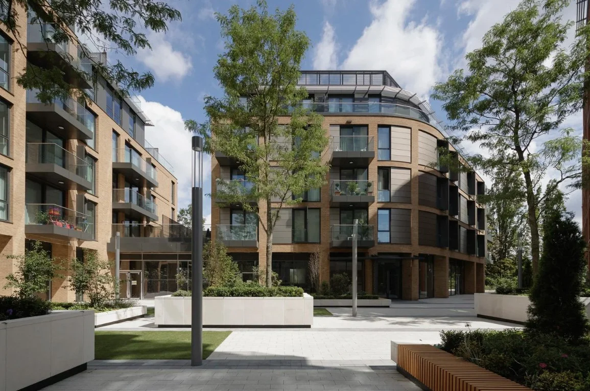Modern building with glass balconies and a tall tree in front.