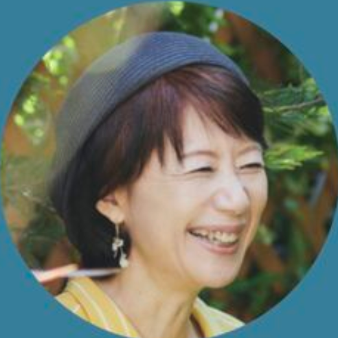 Smiling woman outdoors wearing a gray hat and earrings