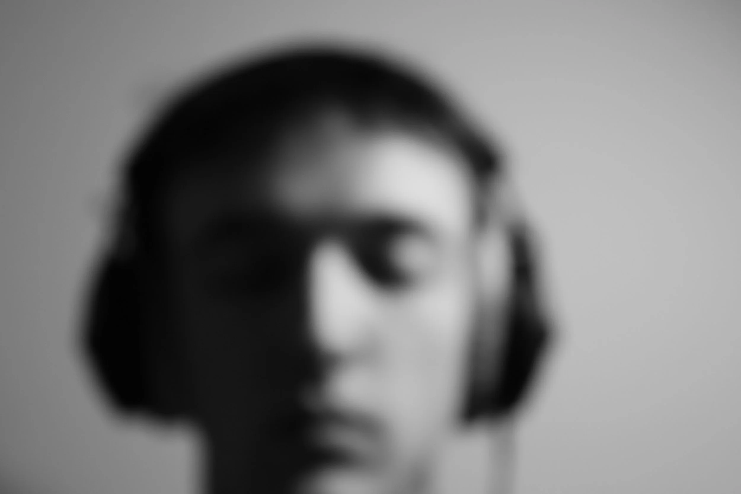 Blurred black and white sculpture of a human face wearing headphones.