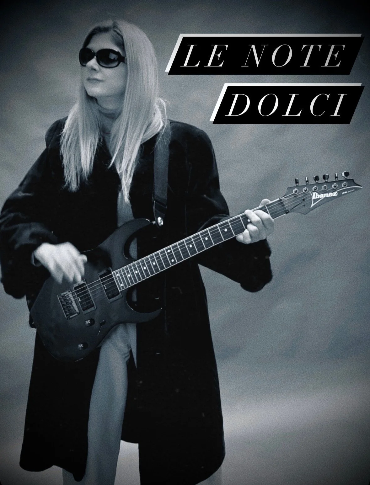 A woman wearing sunglasses playing an Ibanez electric guitar with the text 'Le Note Dolce' in the upper right corner.