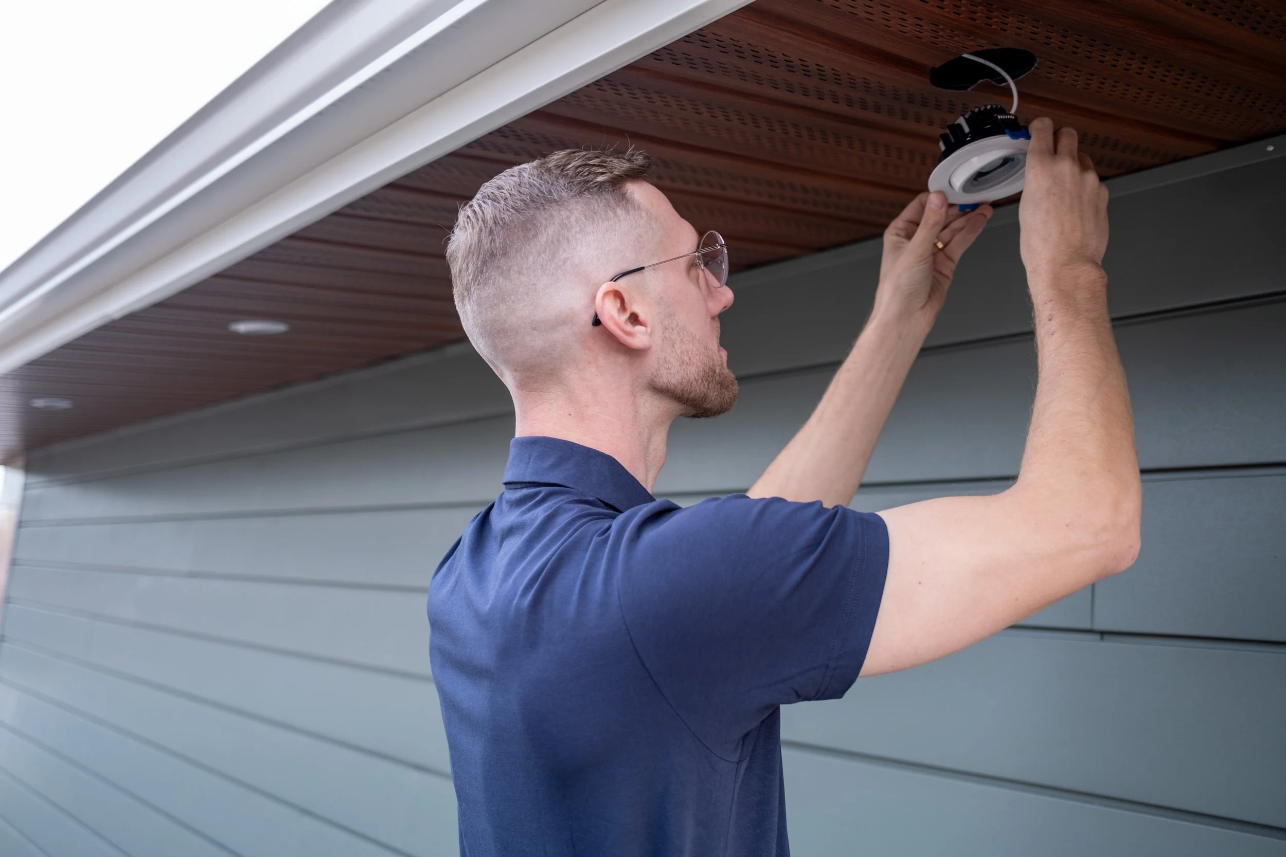 Jesse Tompkins, founder and CEO of Fusesmart Electric in Strathmore, AB, installing exterior lighting on a home