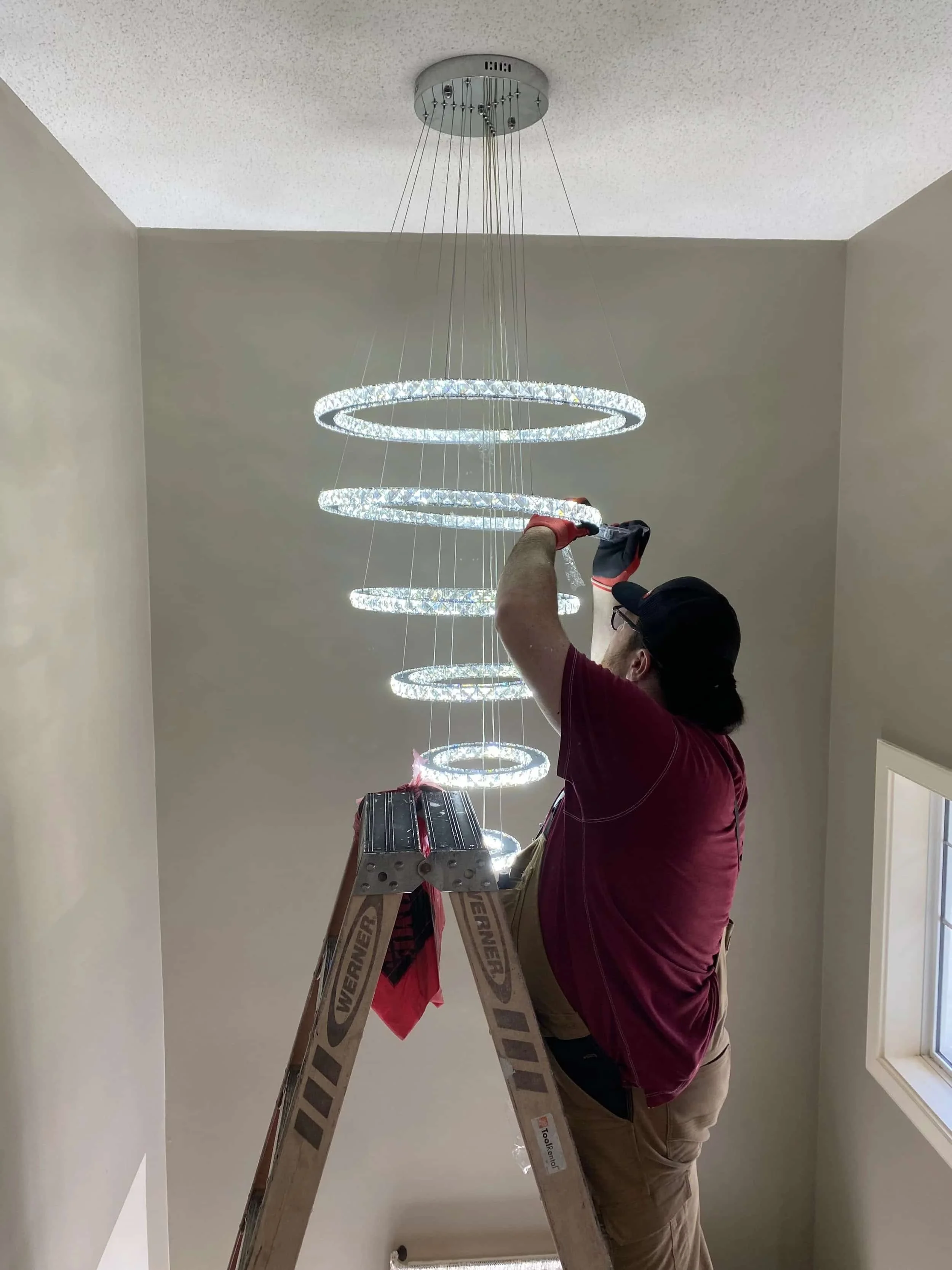 Large chandelier installation with custom electrical support in a Calgary home by FuseSmart Electric.