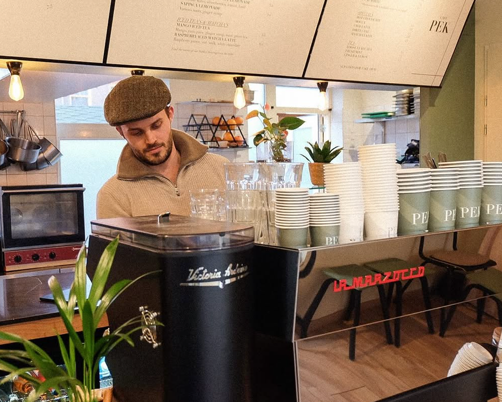 Barista behind the espresso machine at Café PEK