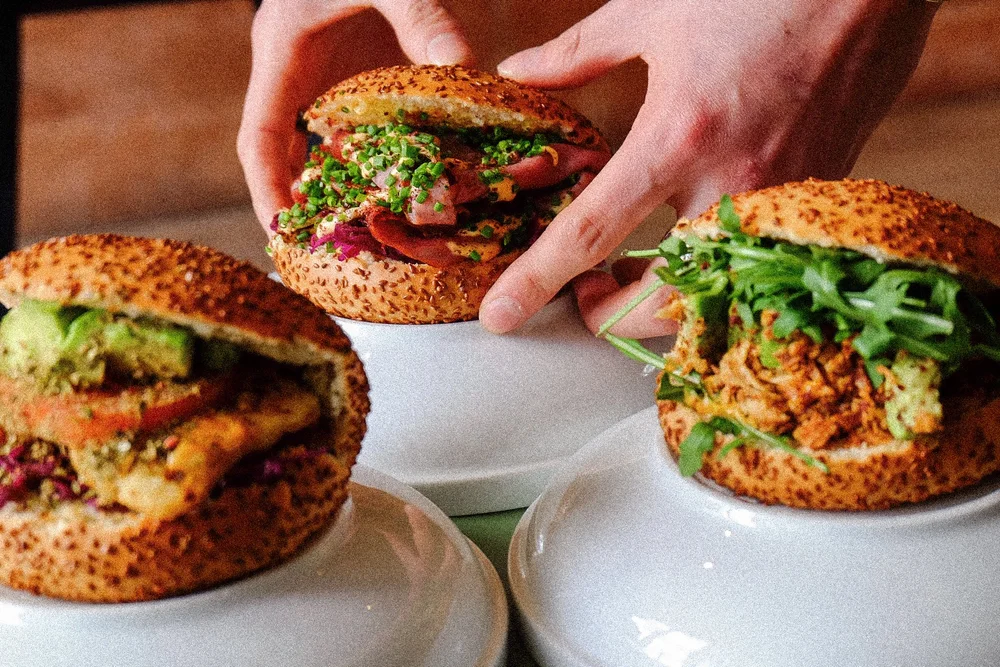 Hands picking up a freshly made simit sandwich