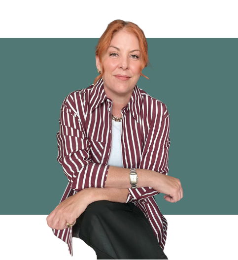 A woman with red hair wearing a striped shirt and a white t-shirt sitting against a teal and white background.