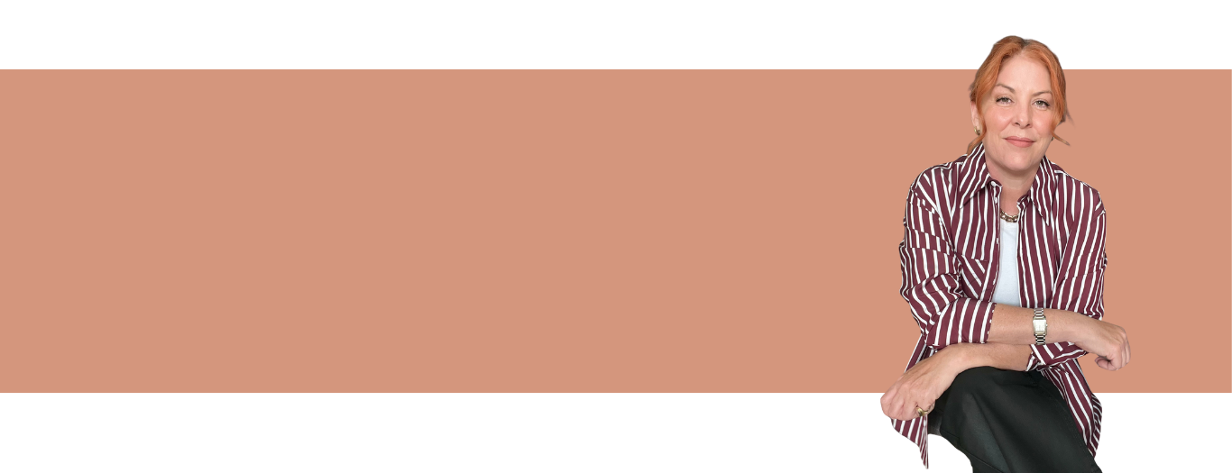 A woman with red hair, wearing a striped maroon and white shirt, sitting on a white surface with a peach-colored background.