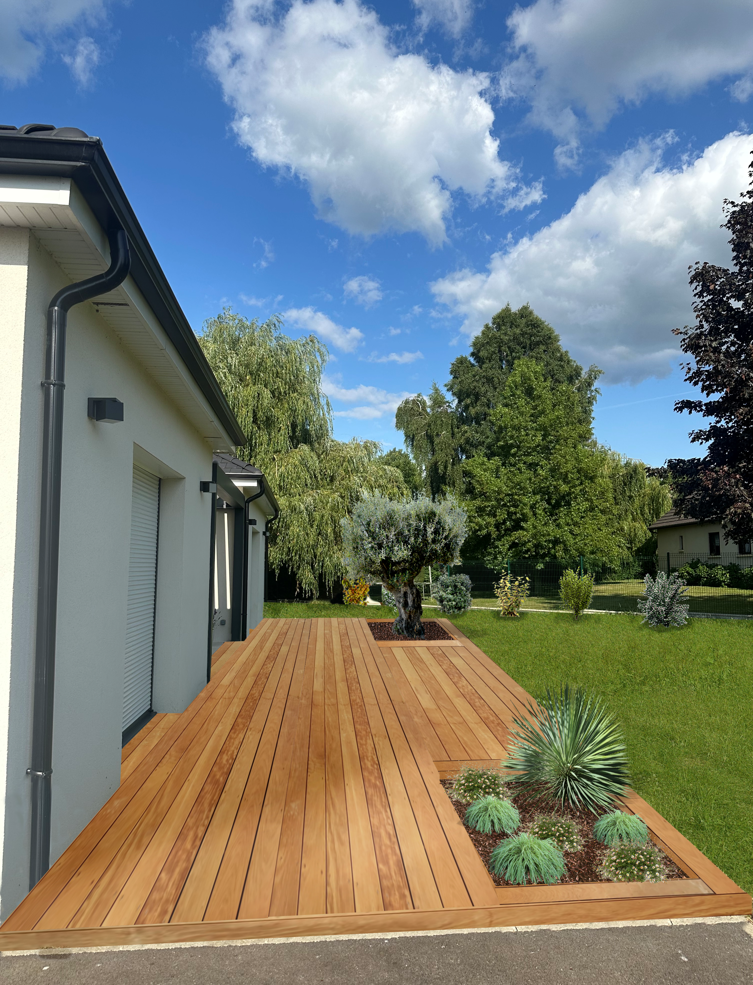 Terrasse en bois devant une maison avec jardin, arbres et ciel bleu avec nuages.