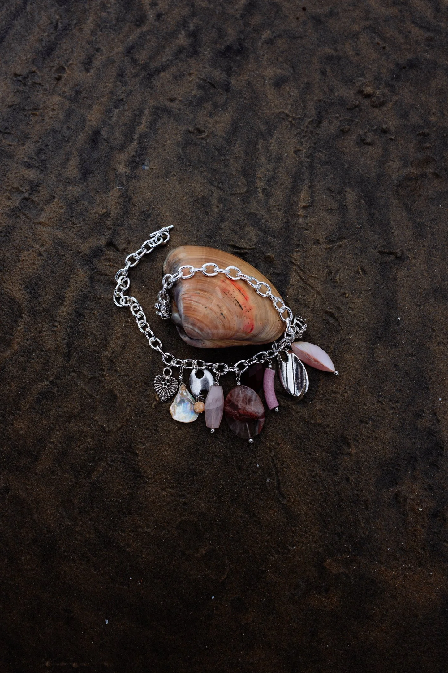 A necklace with charms and beads on a dark, textured surface.
