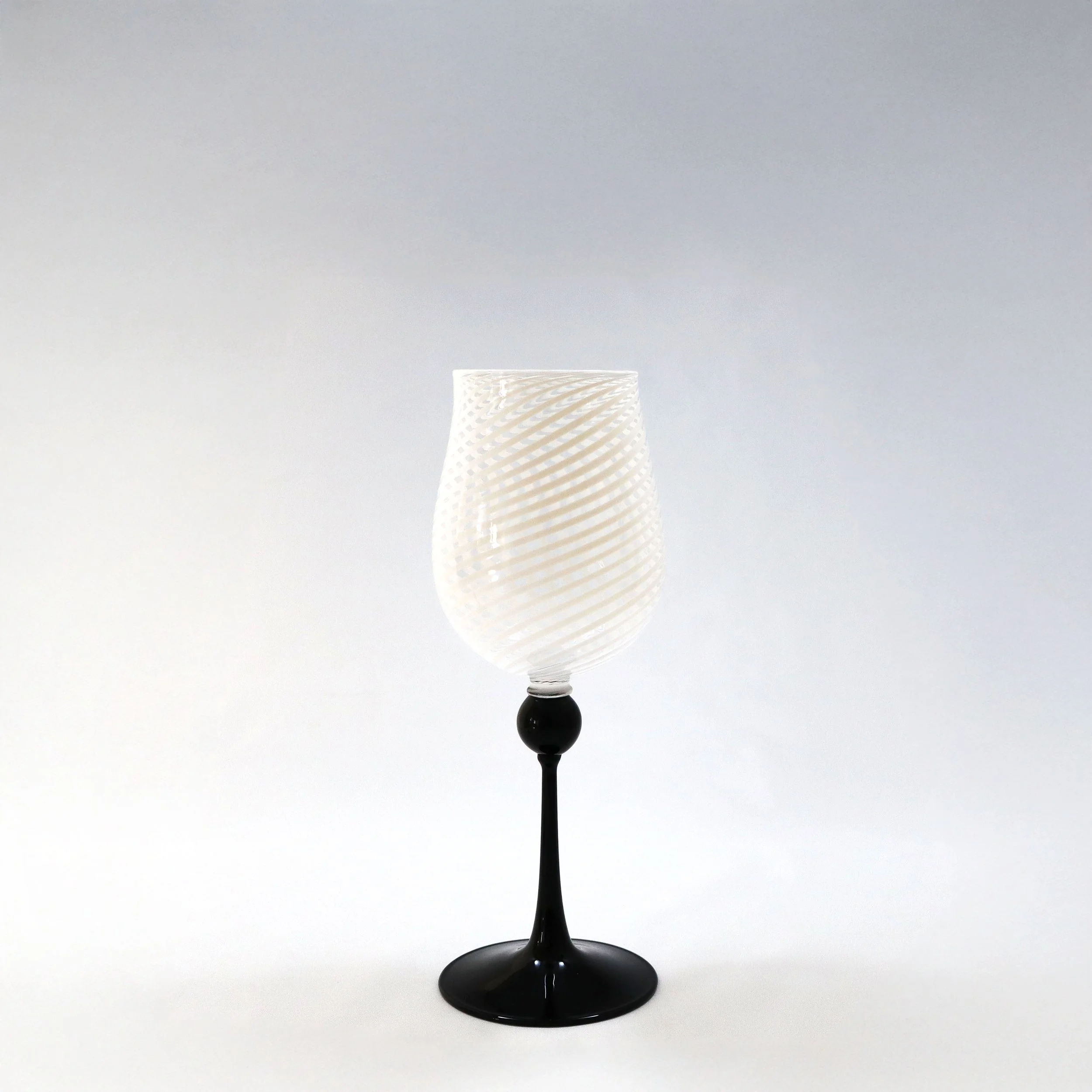 Bicchiere con base nera e fusto alto, con coppa in vetro bianco con motivo a spirale