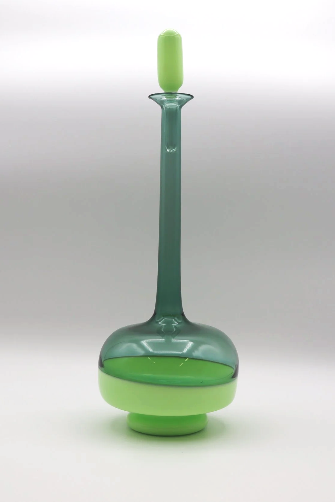 Vasetto di vetro verde con uno stelo lungo e sottile, con una sezione a forma di orbita alla base.
