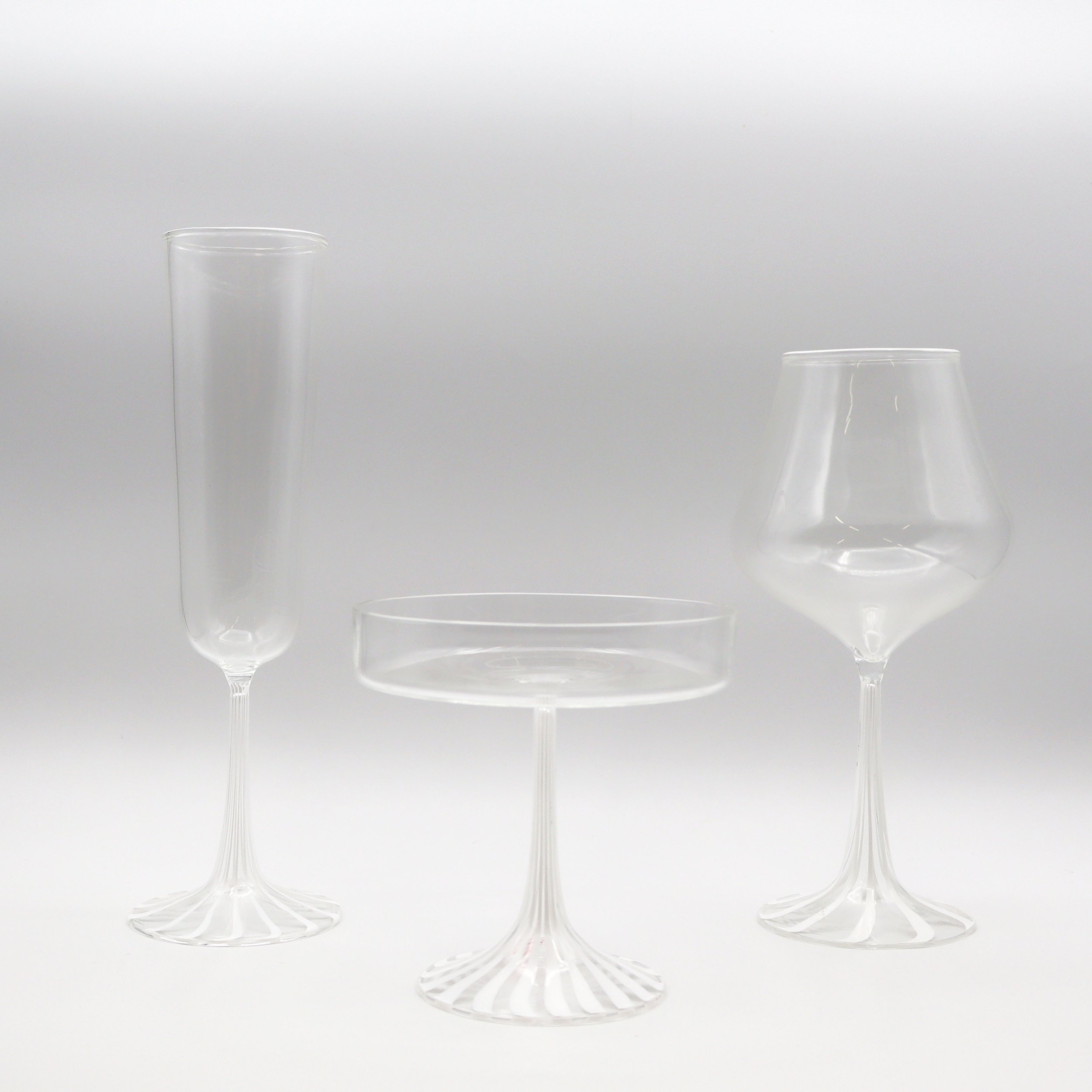 Tre bicchieri di vetro trasparente senza contenuto su uno sfondo bianco.