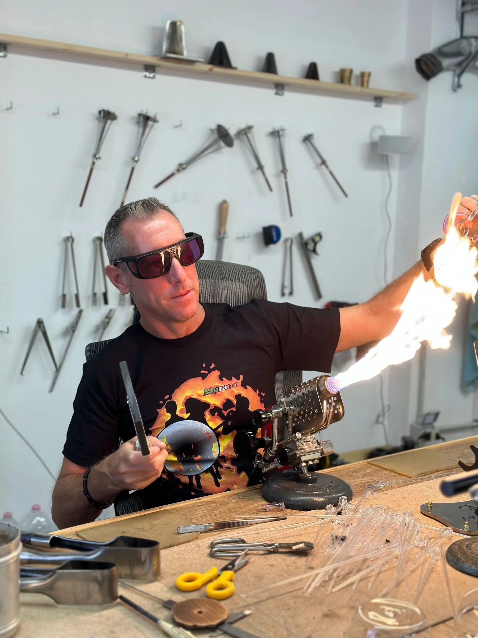 Uomo con occhiali di protezione che lavora a lume in un laboratorio.