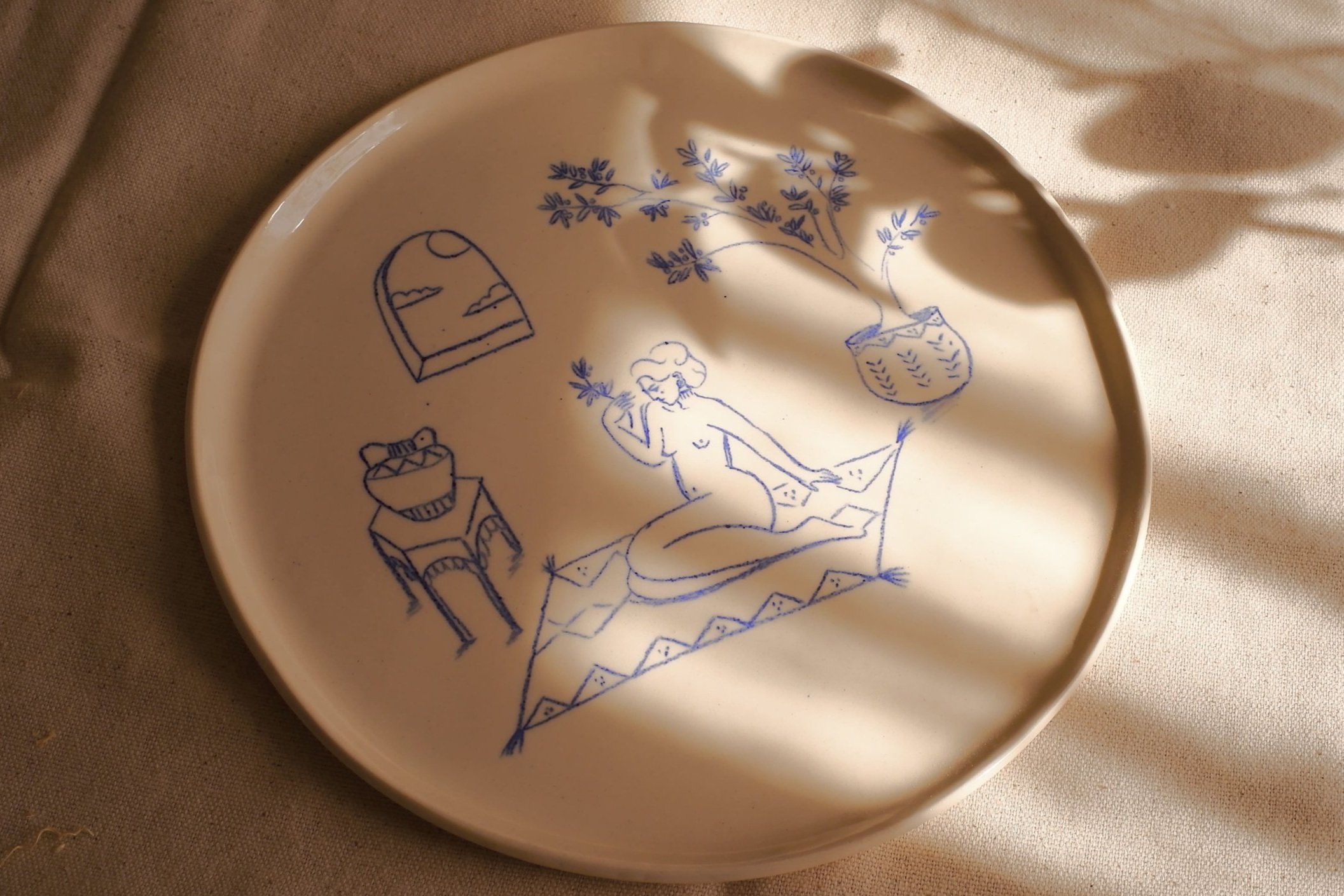 Assiette Eiréna en céramique artisanale, décorée à la main avec des illustrations uniques de la déesse Eiréné dans son jardin intérieur. Allie art et élégance.