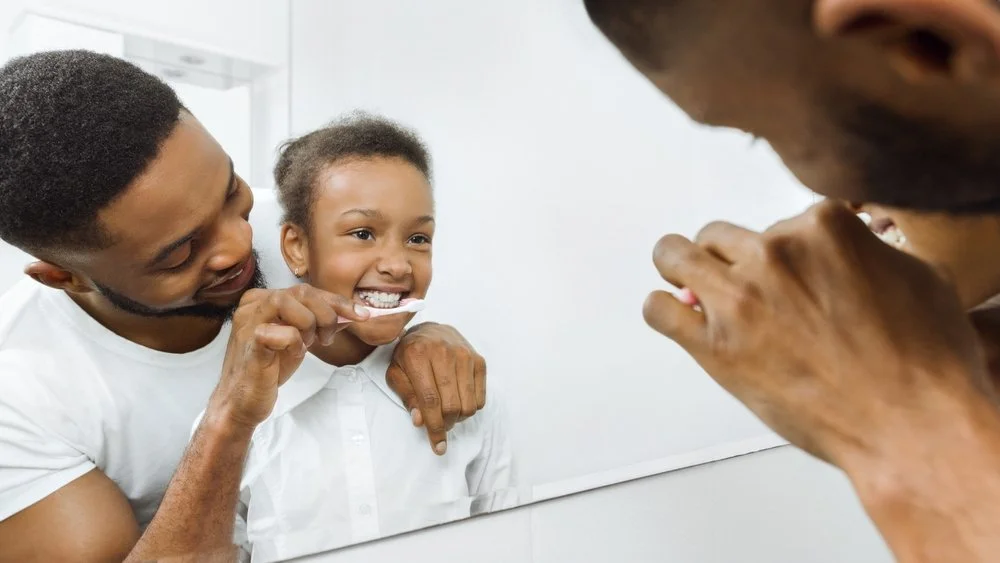 family brushing teeth together at home demonstrating daily oral care routine for family dentistry