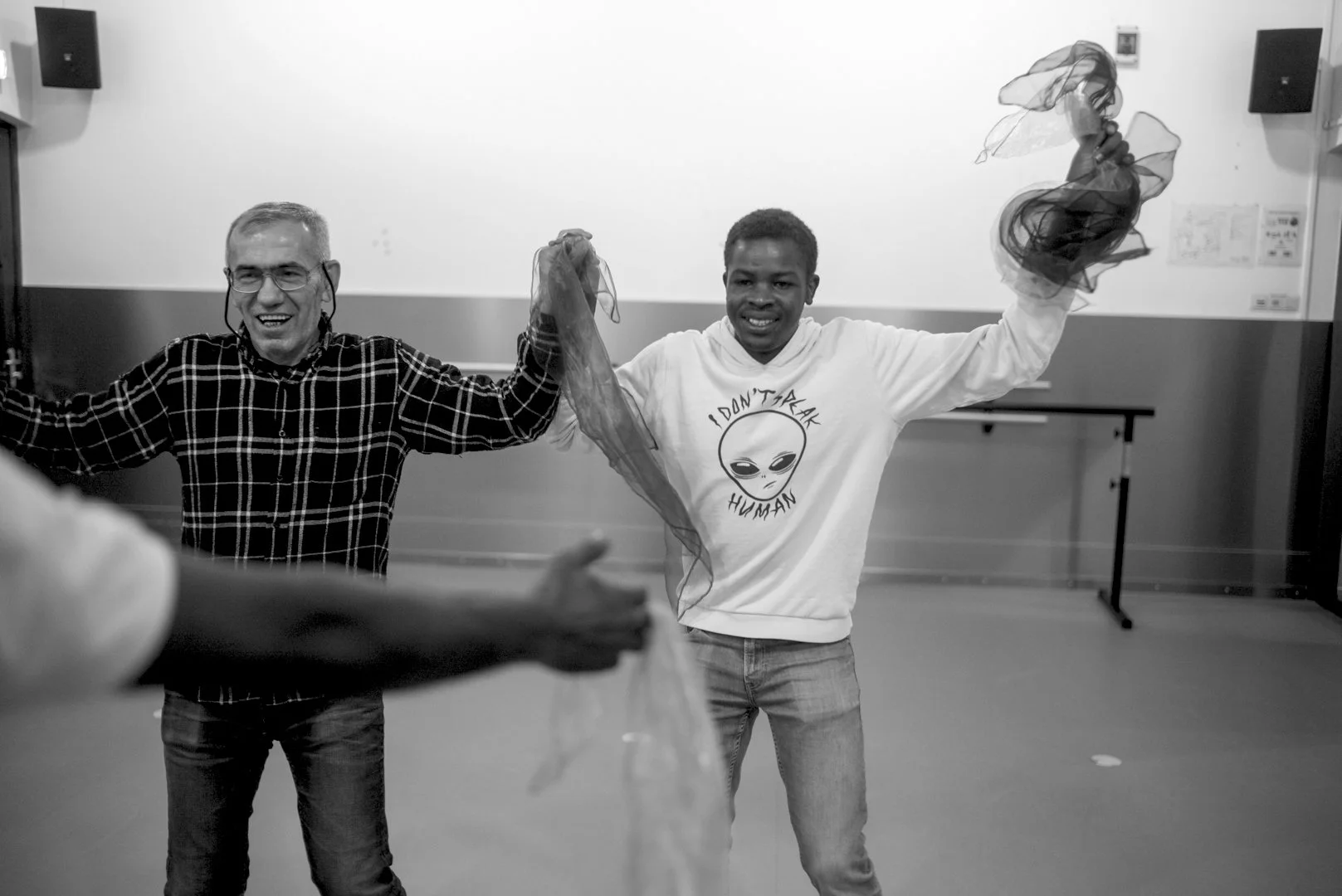 Twee jonge asielzoekers lachen naar elkaar tijdens een dansworkshop; even kunnen ze hun zorgen loslaten, elkaars handen vasthouden en gewoon in het moment zijn.