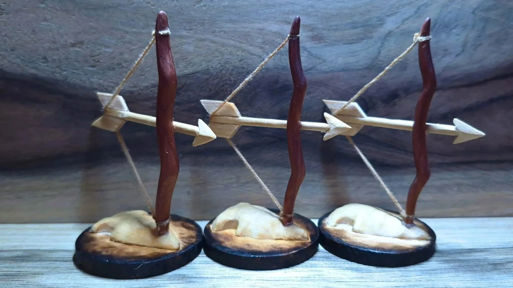 Miniature wooden bows and arrows, mounted on round bases.