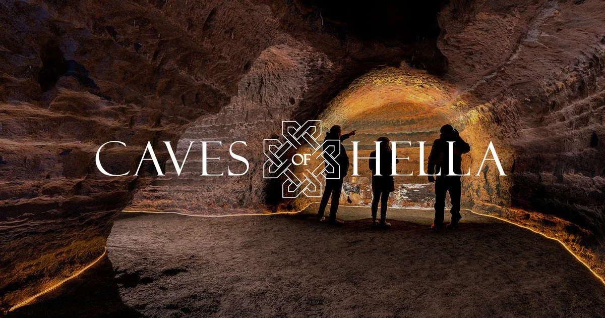 Silhouettes of three people inside a large cave with rock walls and ceiling, illuminated by warm lighting, and text that reads 'Caves of Hella' in front of the scene.
