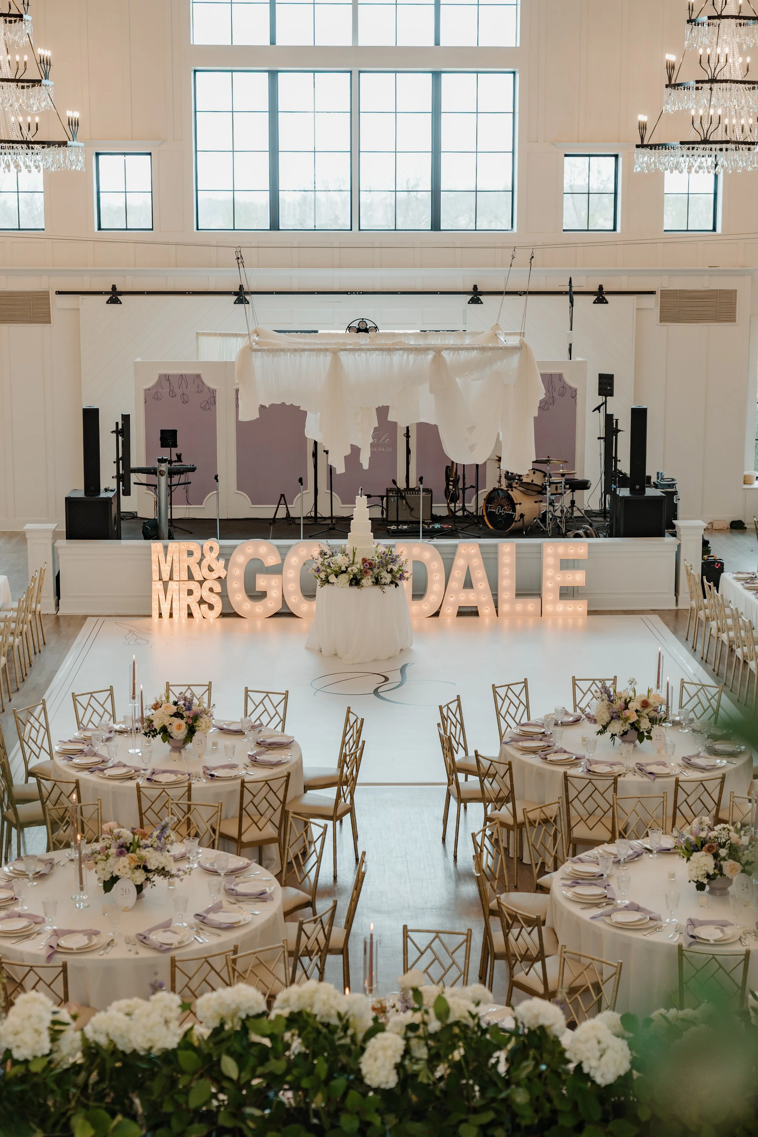 Wide reception shot with MR & MRS GOODALE marquee letters, KC skyline backdrop, round tables, chandeliers