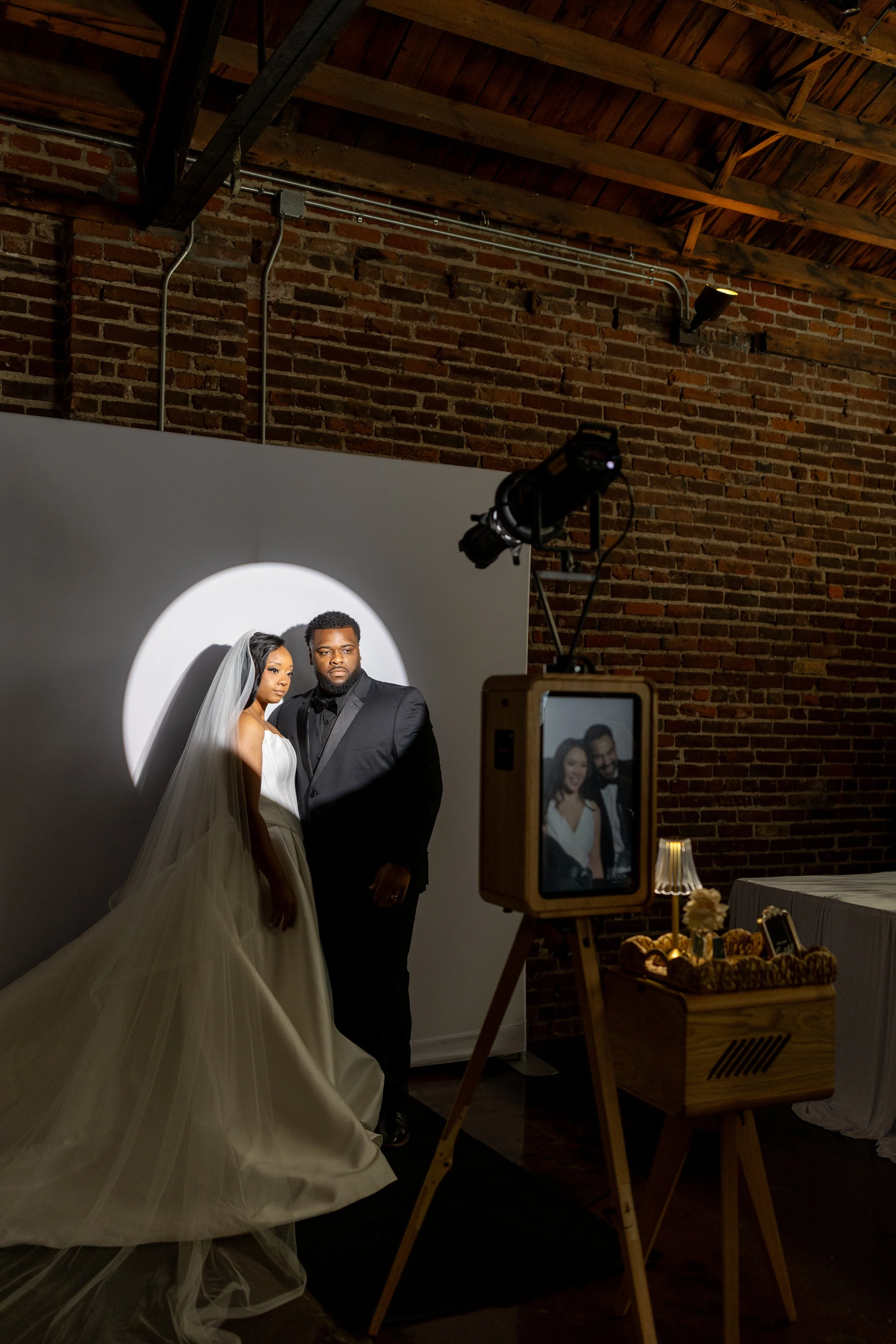 Bride and groom posing in a spotlight style photo booth at The Guild wedding venue in Kansas City with studio lighting and modern backdrop