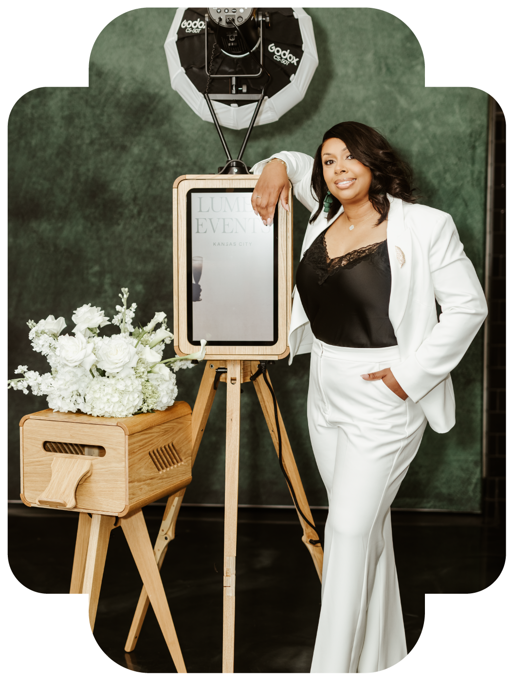 Lumen Events Kansas City owner with vintage wooden photo booth and emerald green velvet backdrop
