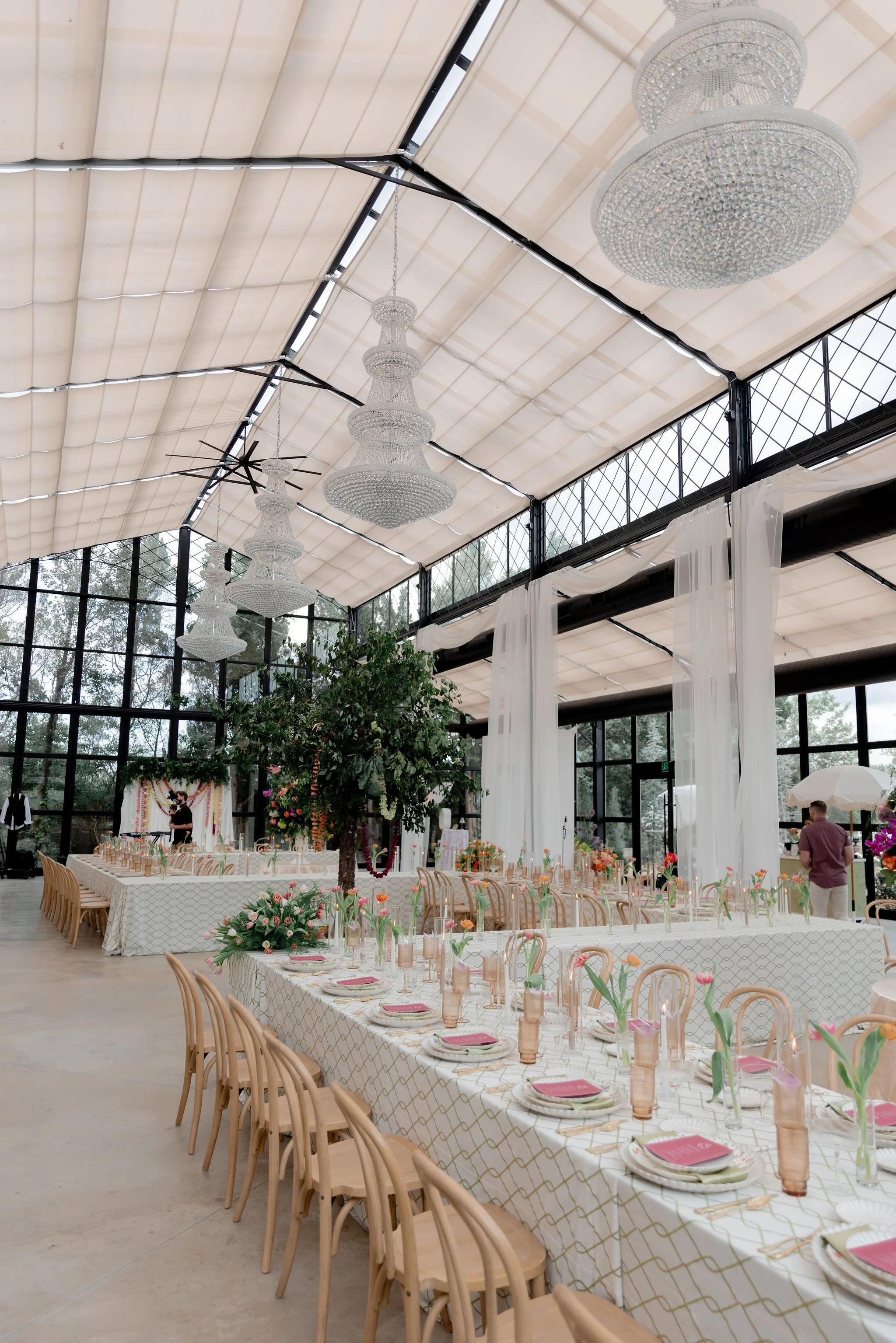 Styled reception tables with crystal chandeliers and florals inside The Glasshouse at River Oaks Kansas City open house