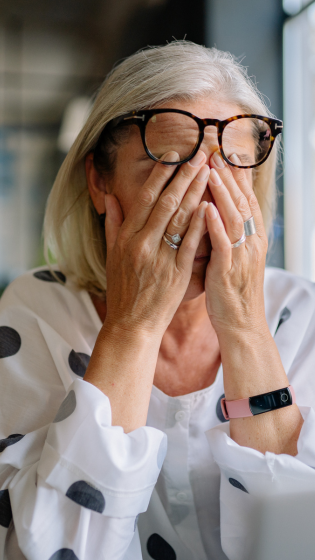 Woman covering her face with hands looking overwhelmed — signs of people-pleasing burnout and anxiety