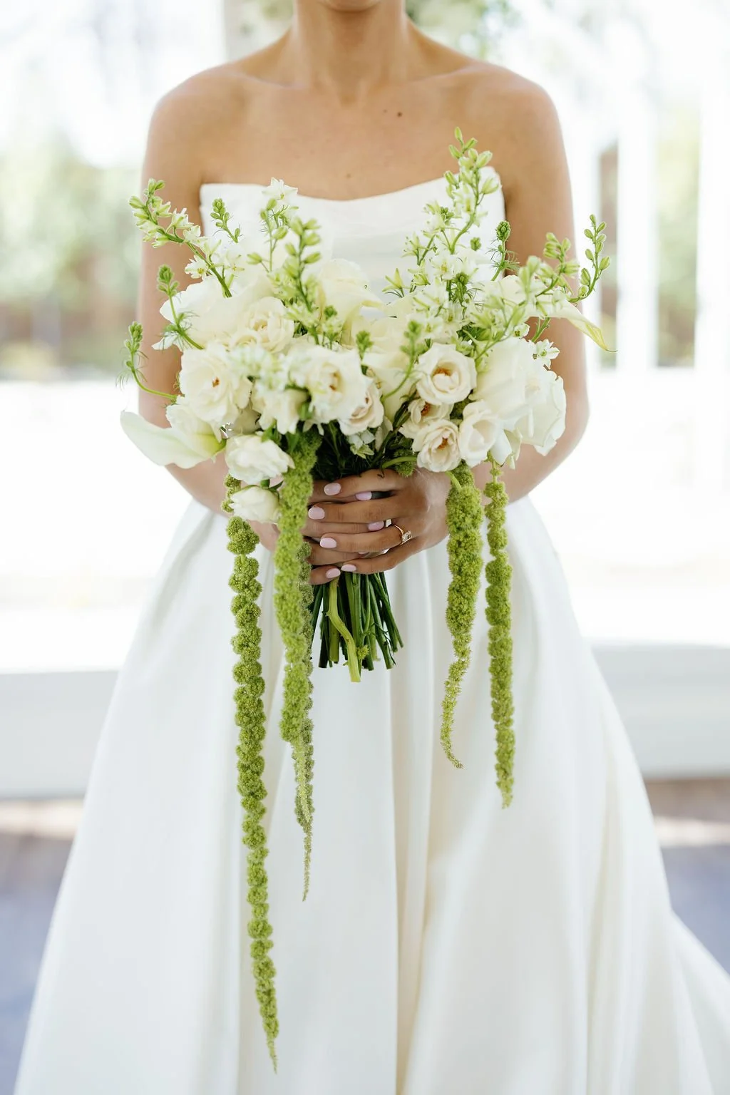 A bridal bouquet by Haute Poppies Floral, with white garden roses, lisianthus, and trailing green hanging amaranthus