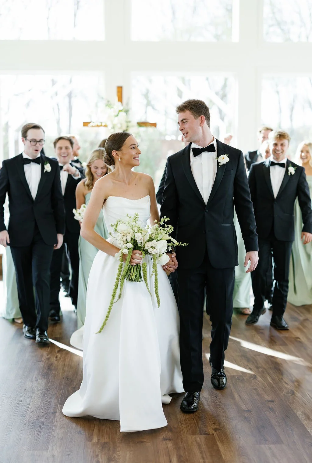 A bride and groom holding hands in their wedding ceremony space, at River Road in Anna, Texas
