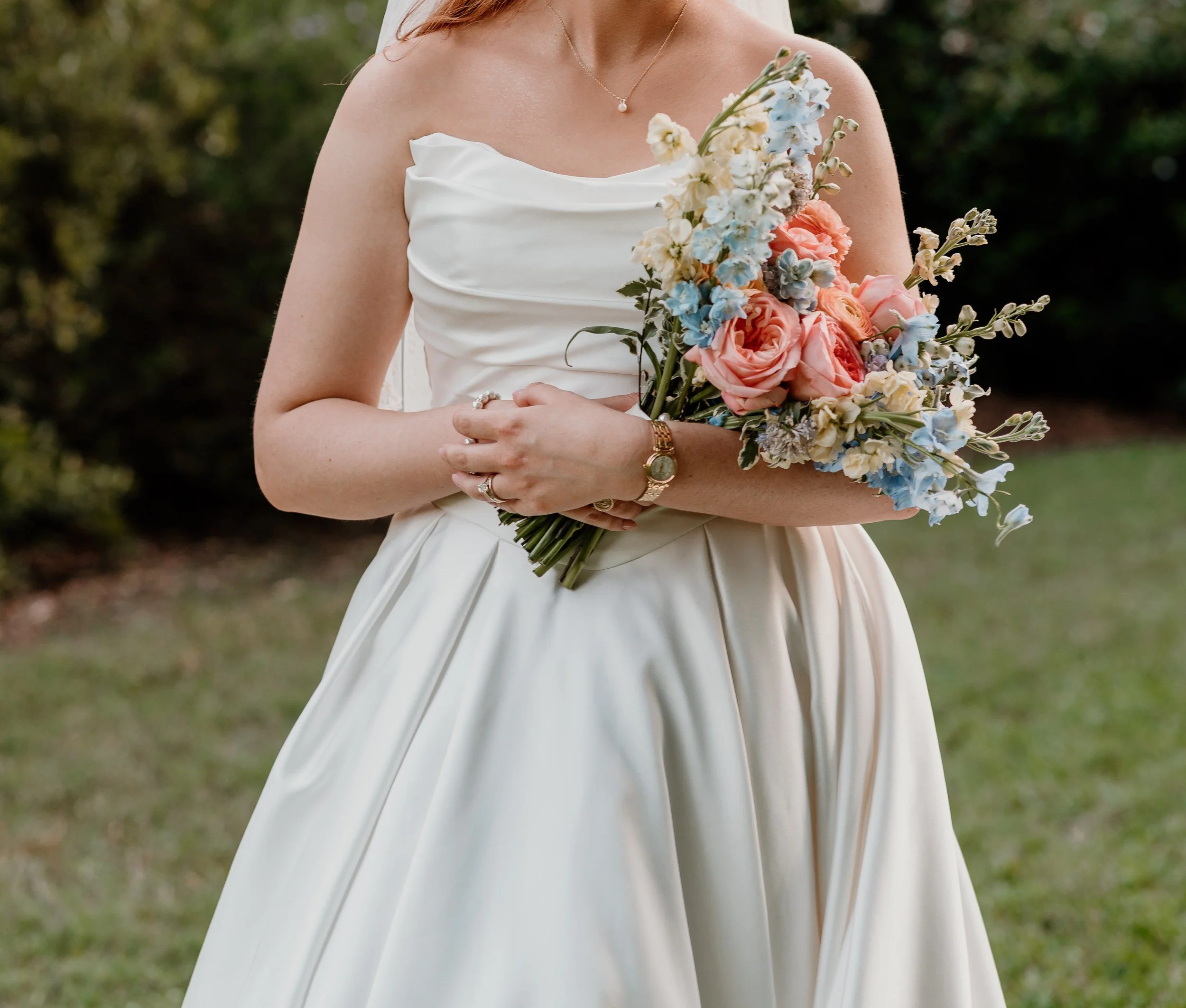 Bride holding a loose bouquet of peach roses and pale blue flowers at The RoseMary
