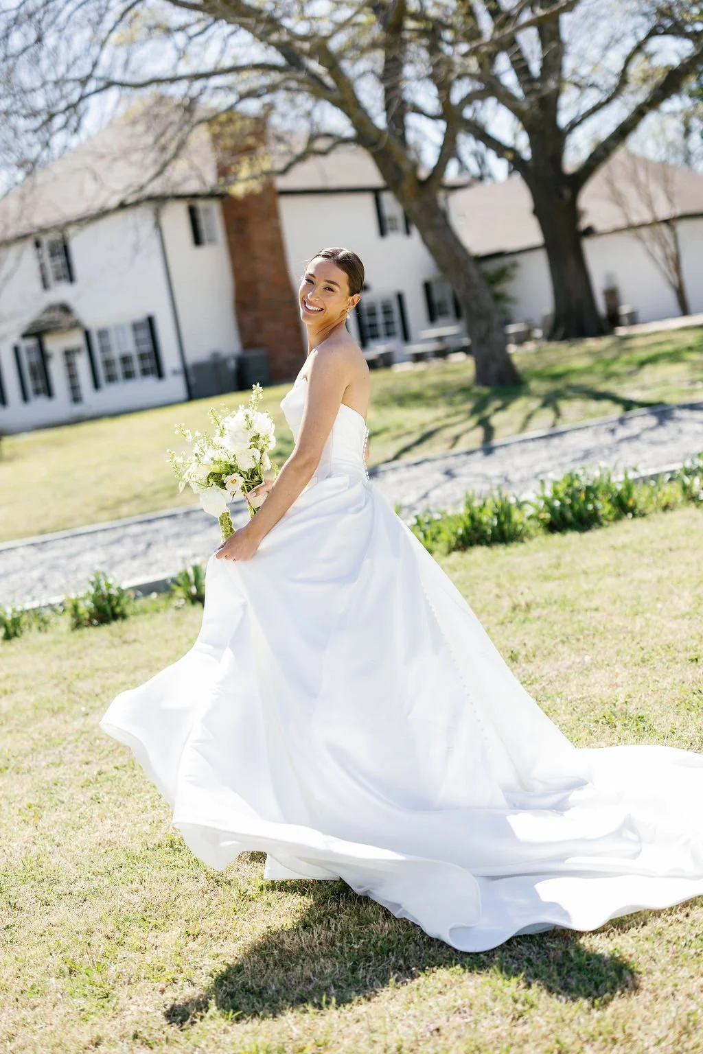 A bride in a satin gown, taking pictures at River Road Venue