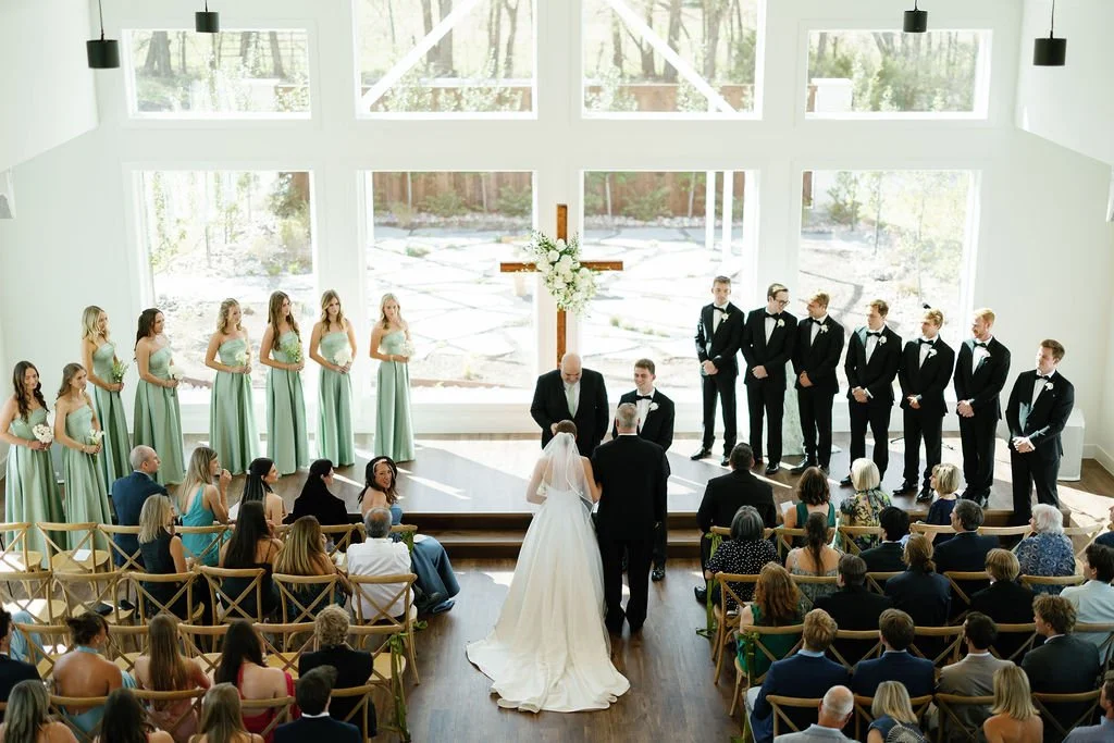 A bride walking down the aisle at River Road Venue, with her father