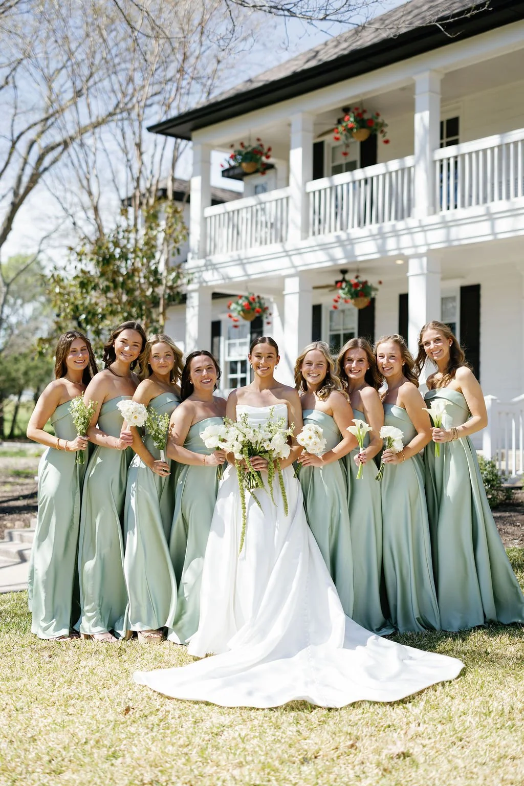 Bridesmaids in sage green satin gowns, holding single flower bouquets - including roses, garden roses, parrot tulips, and calla lilies