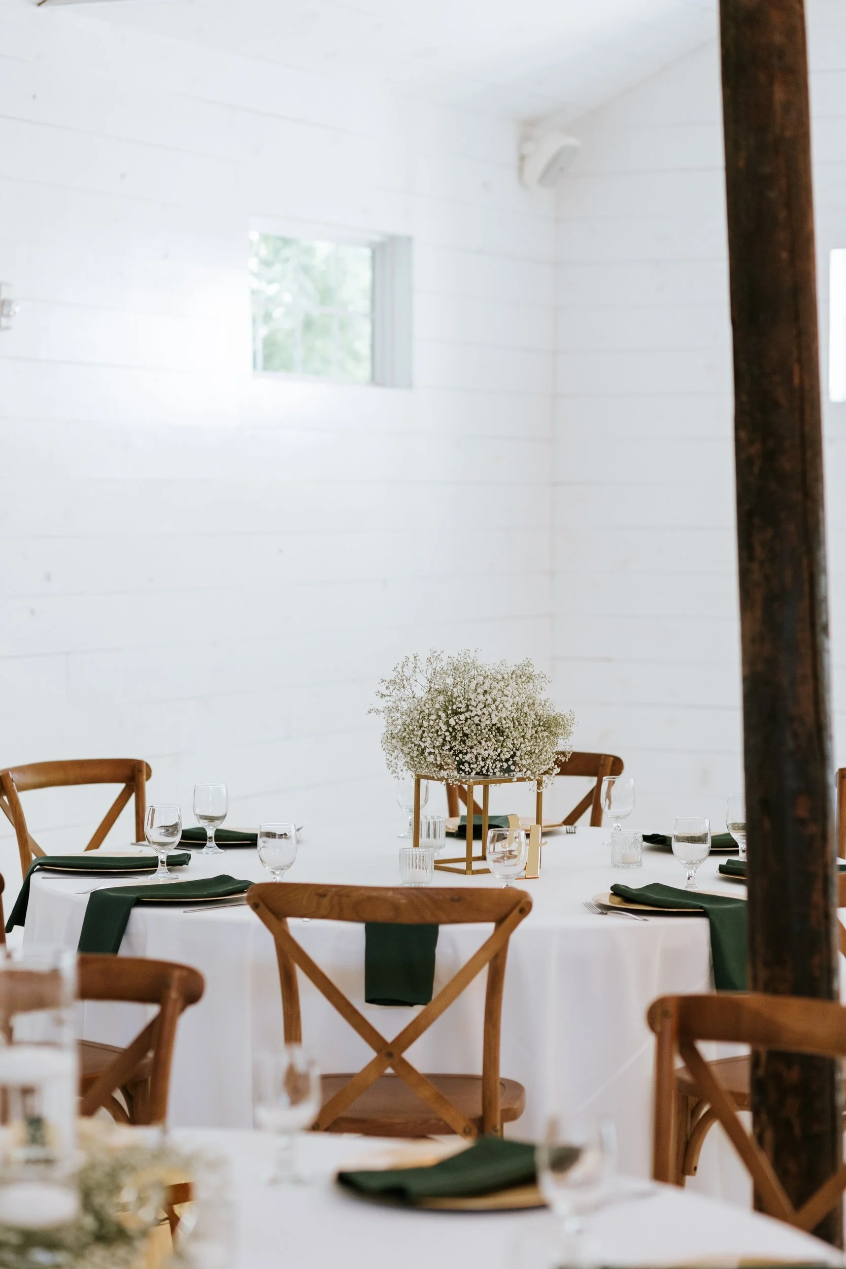 White reception hall with wood chairs and a small white floral centerpiece
