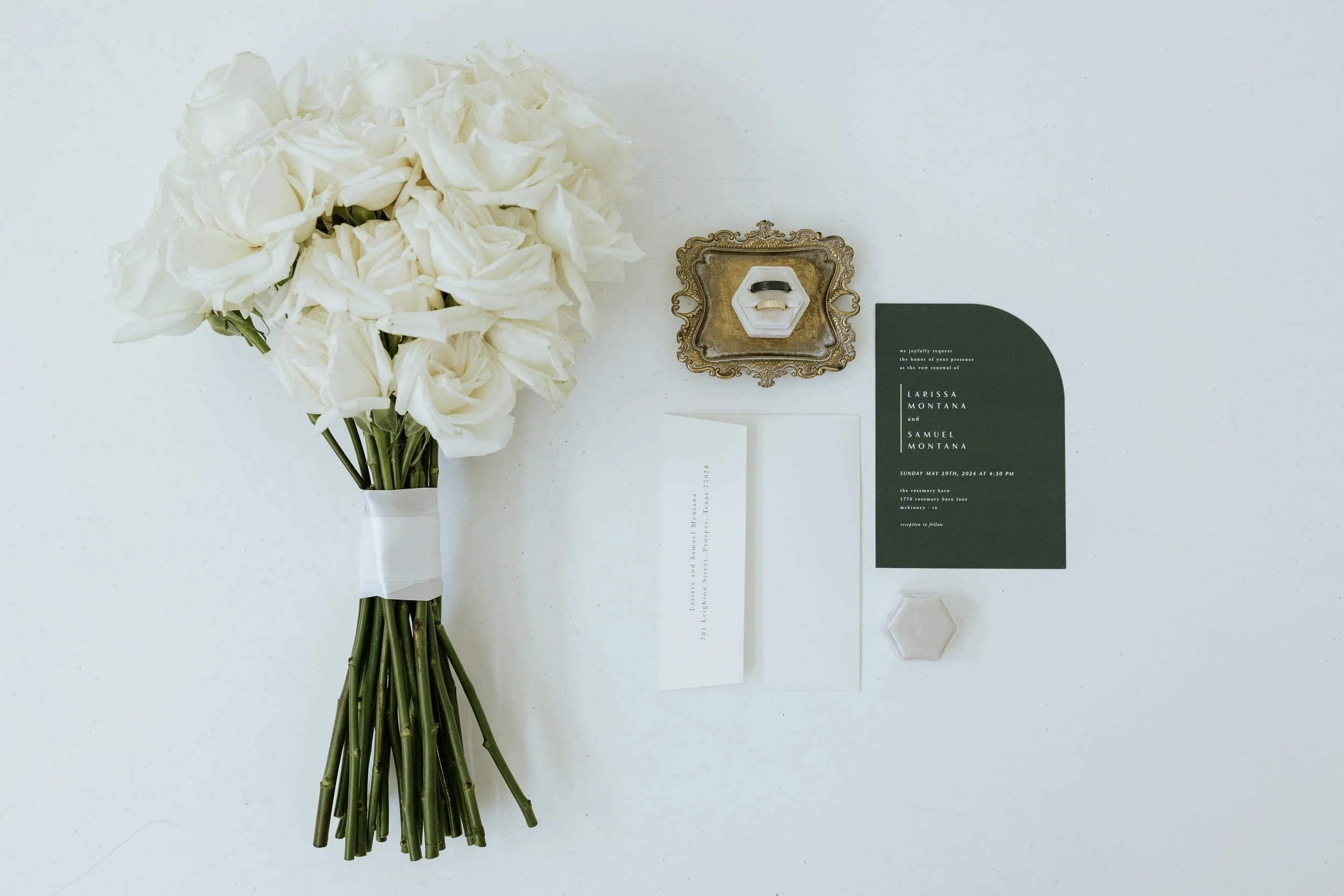 White bridal bouquet tied with ribbon beside a wedding invitation suite
