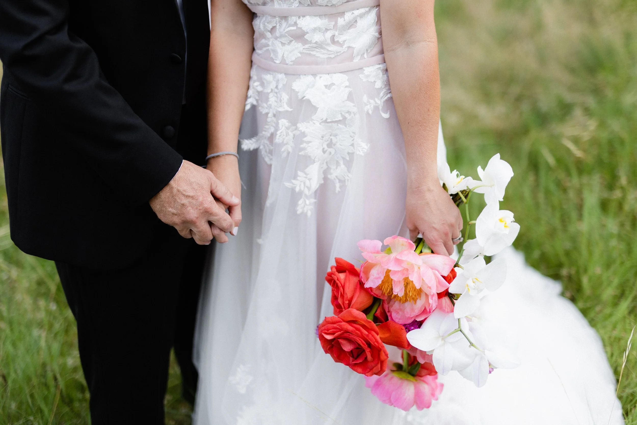 Bride holding a coral and pink bouquet beside her groom