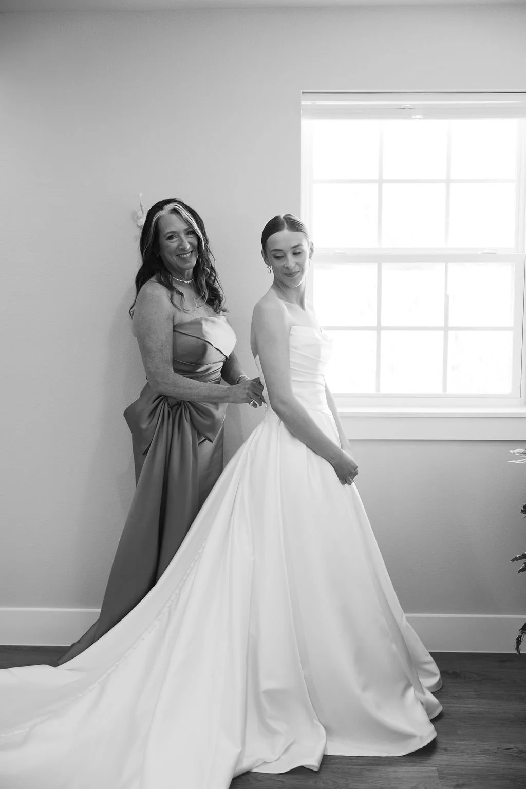 A bride getting ready at River Road Venue, with her mom zipping up her dress