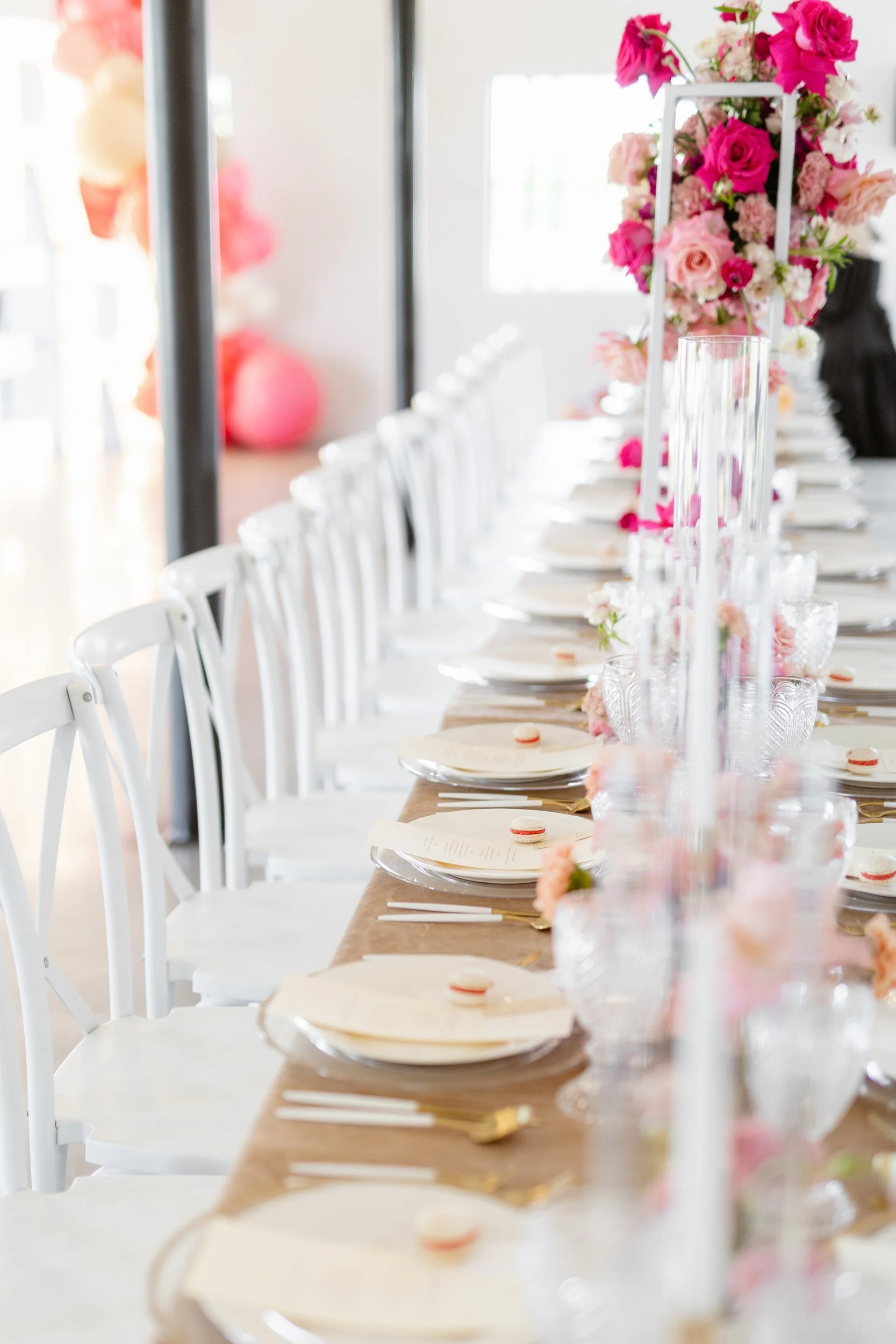 Long reception table with tall clear stands topped with pink and red flowers