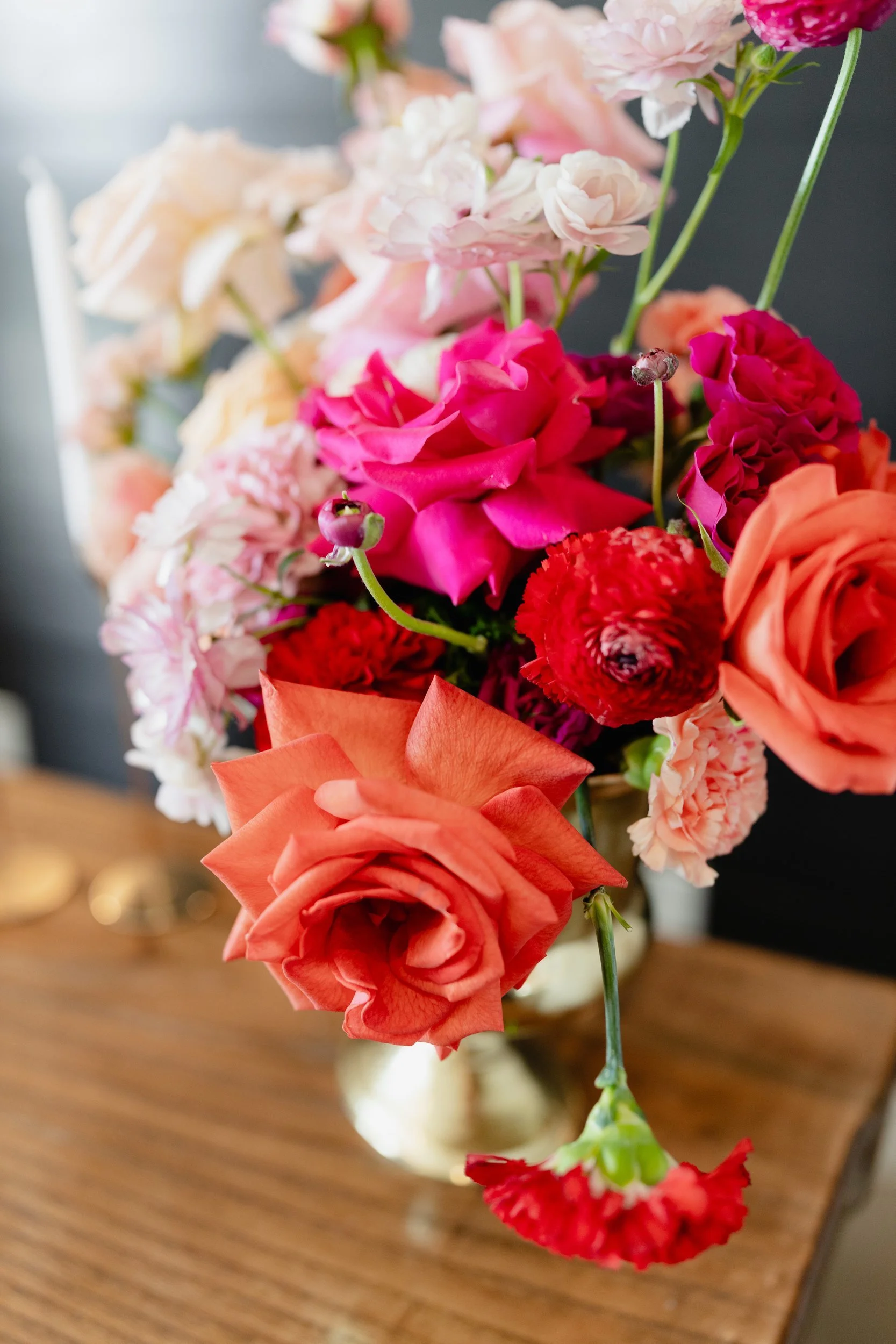 Close view of coral and hot pink roses in a gold compote