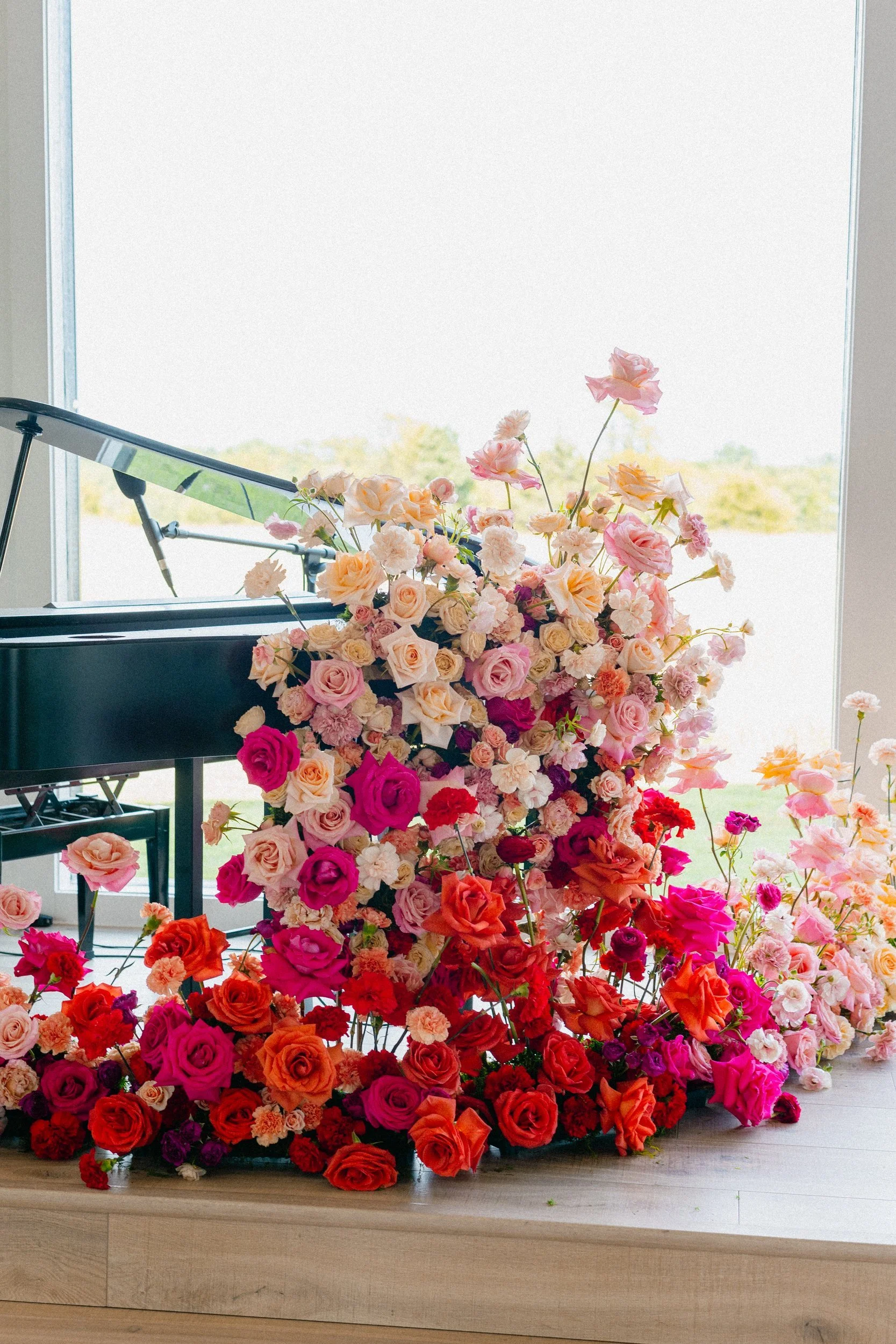 Pink, coral and red rose installation cascading beside a grand piano